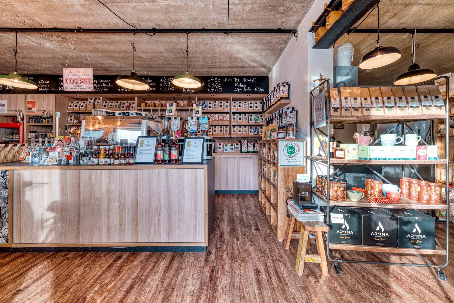 Innenansicht eines Hofladens oder Cafés mit Holztheke, Regalen und Produkten.