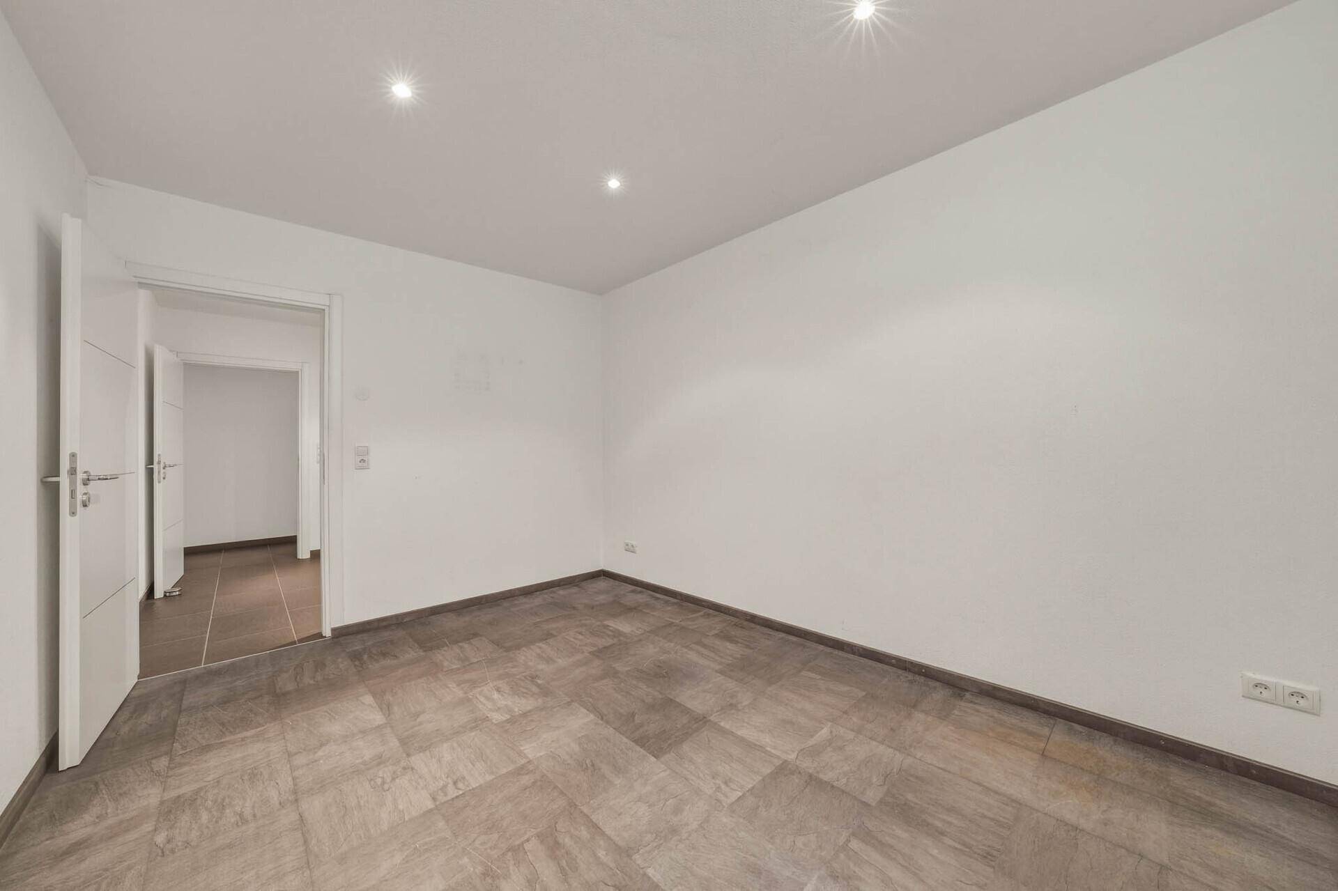Leeres Zimmer mit Fliesenboden und weiß gestrichenen Wänden, ideal für individuelle Nutzung.