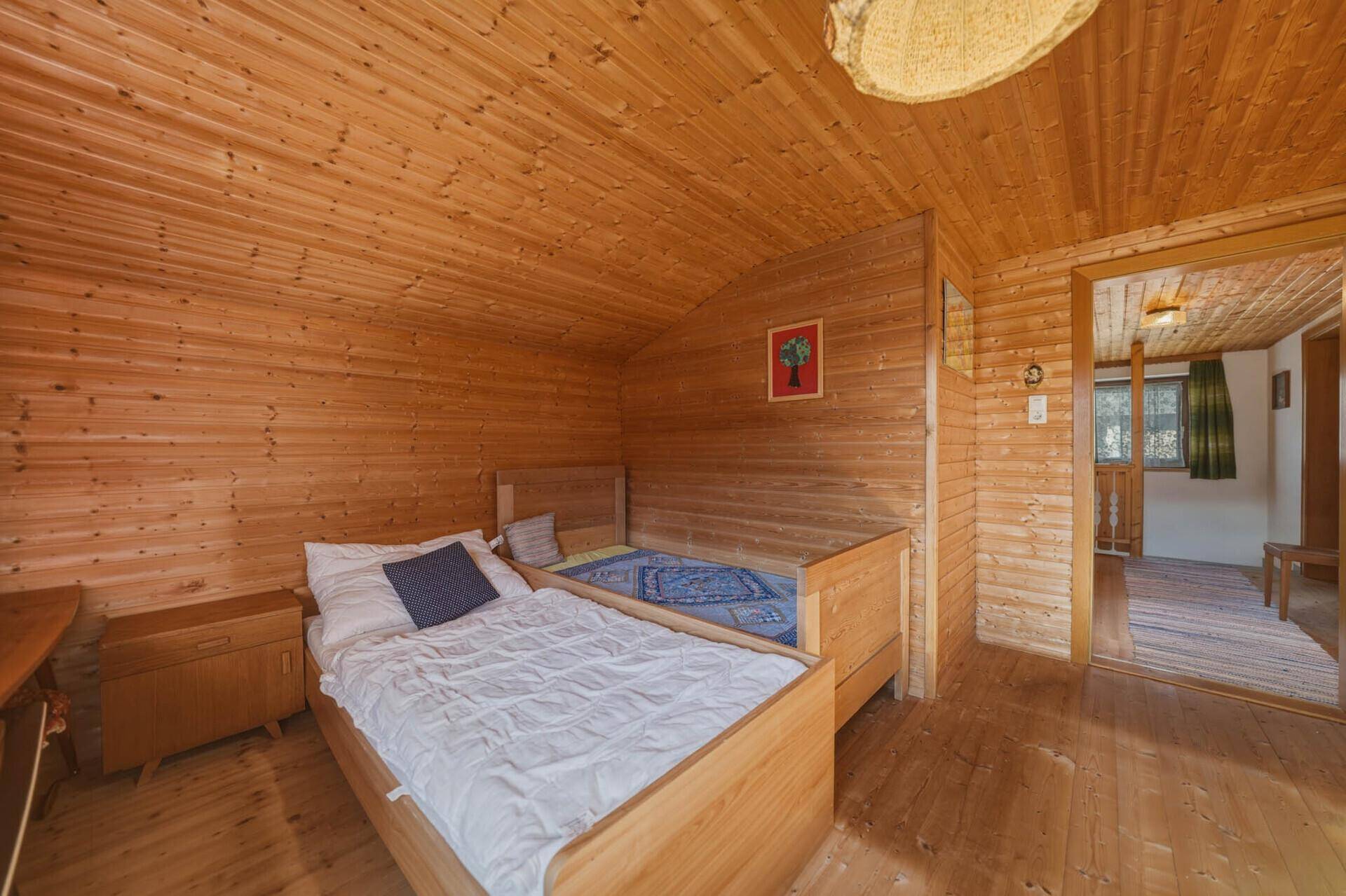 Gemütliches Schlafzimmer mit Holztäfelung, zwei Einzelbetten und Dachschräge.