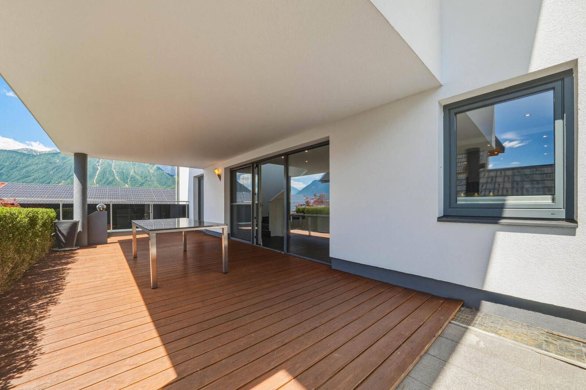 Geräumige Terrasse mit Holzdielenboden, modernem Tisch und beeindruckendem Bergblick.
