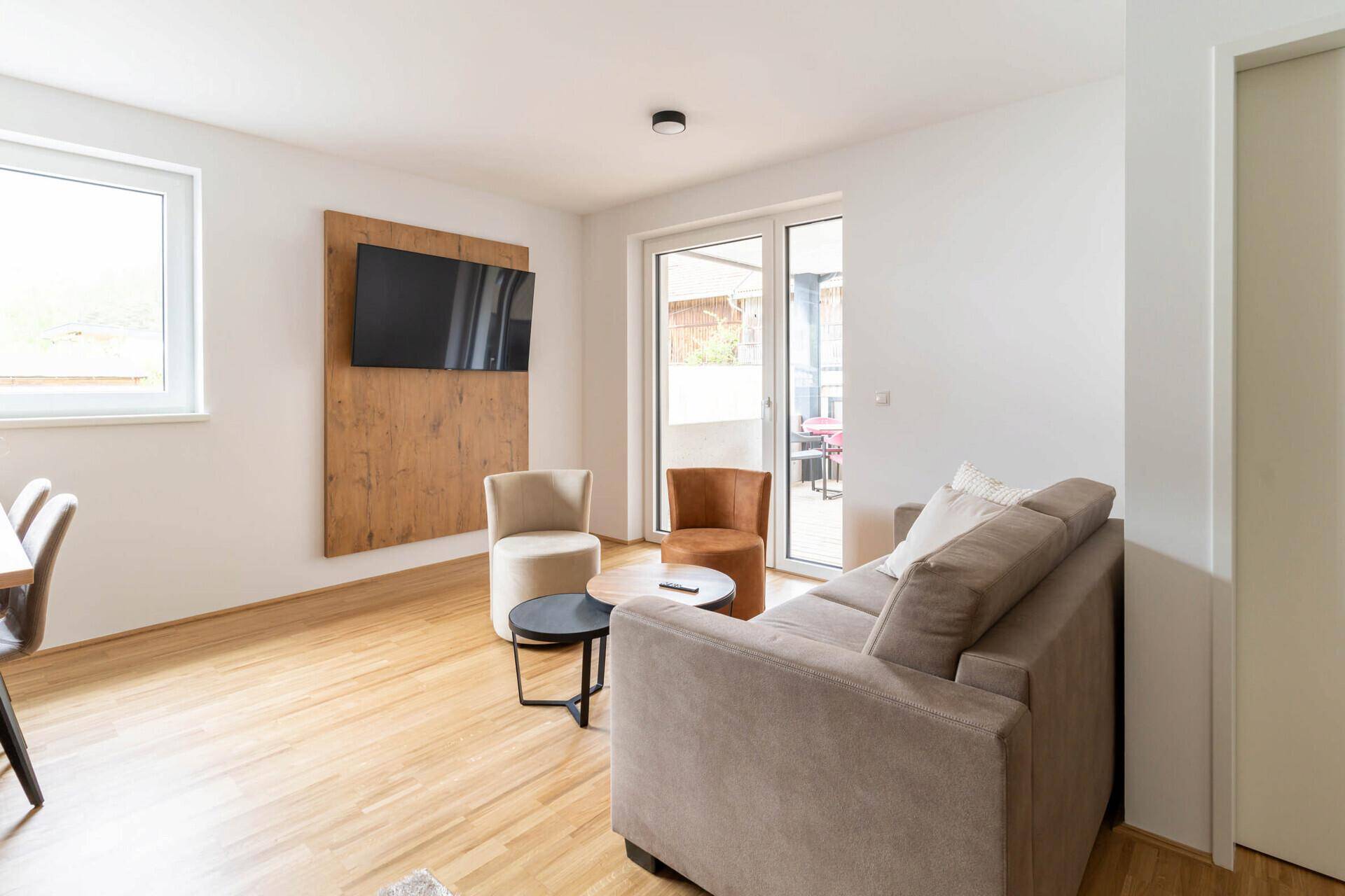 Heller Wohn-Essbereich mit Holzboden, Esstisch und Zugang zum Balkon.