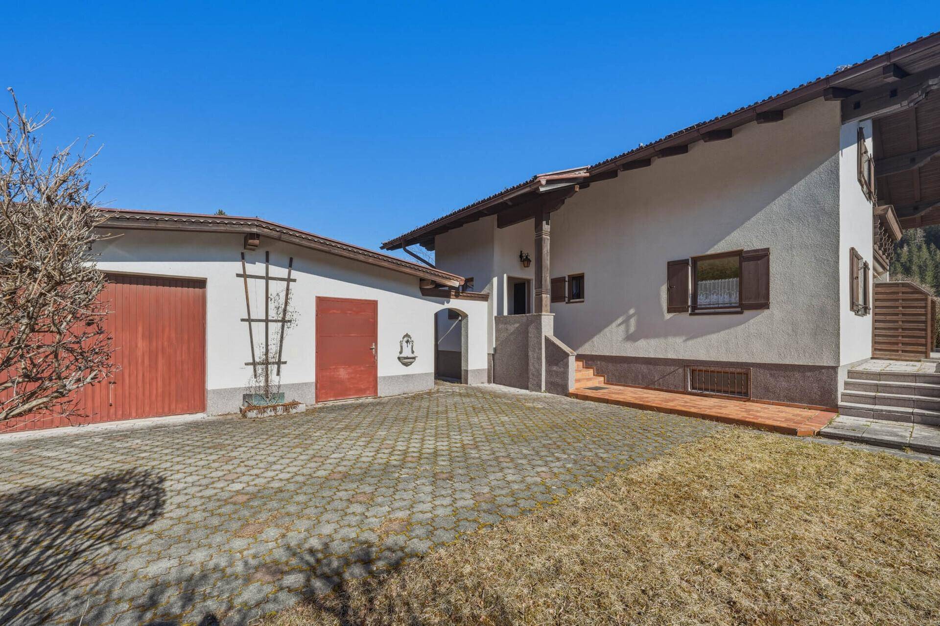 Hausfassade mit Garage, gepflasterter Auffahrt und Bergblick.