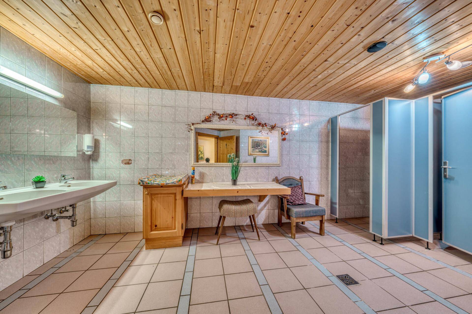 Geräumiger Toilettenbereich mit mehreren Waschbecken, Spiegeln und Holzbalkendecke.