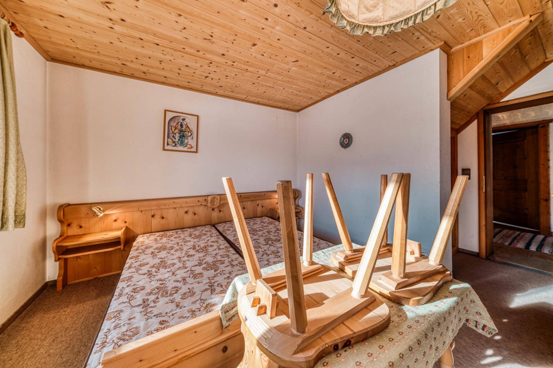 Gemütliches Schlafzimmer mit Holzdecke, Teppichboden und traditionellen Holzmöbeln.