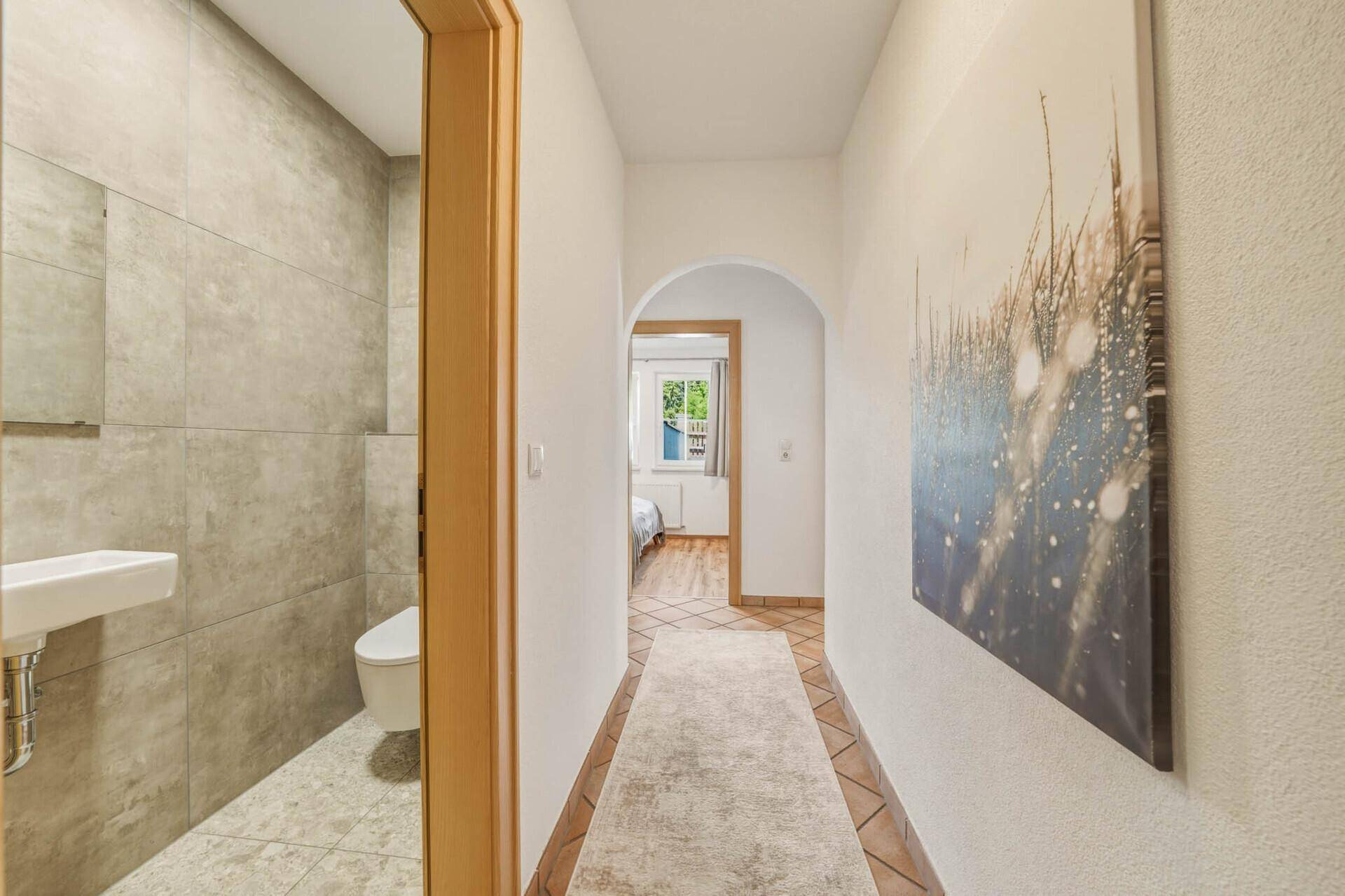Heller Flur mit Terrakottafliesen, der zu einem Schlafzimmer und einem kleinen WC-Bereich führt.