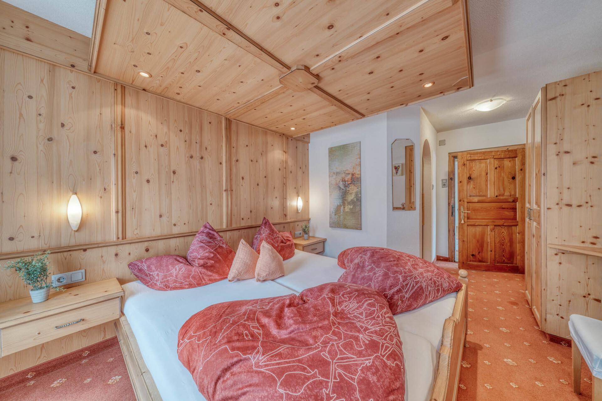 Gemütliches Schlafzimmer im alpinen Stil mit Holzvertäfelung und Doppelbett.