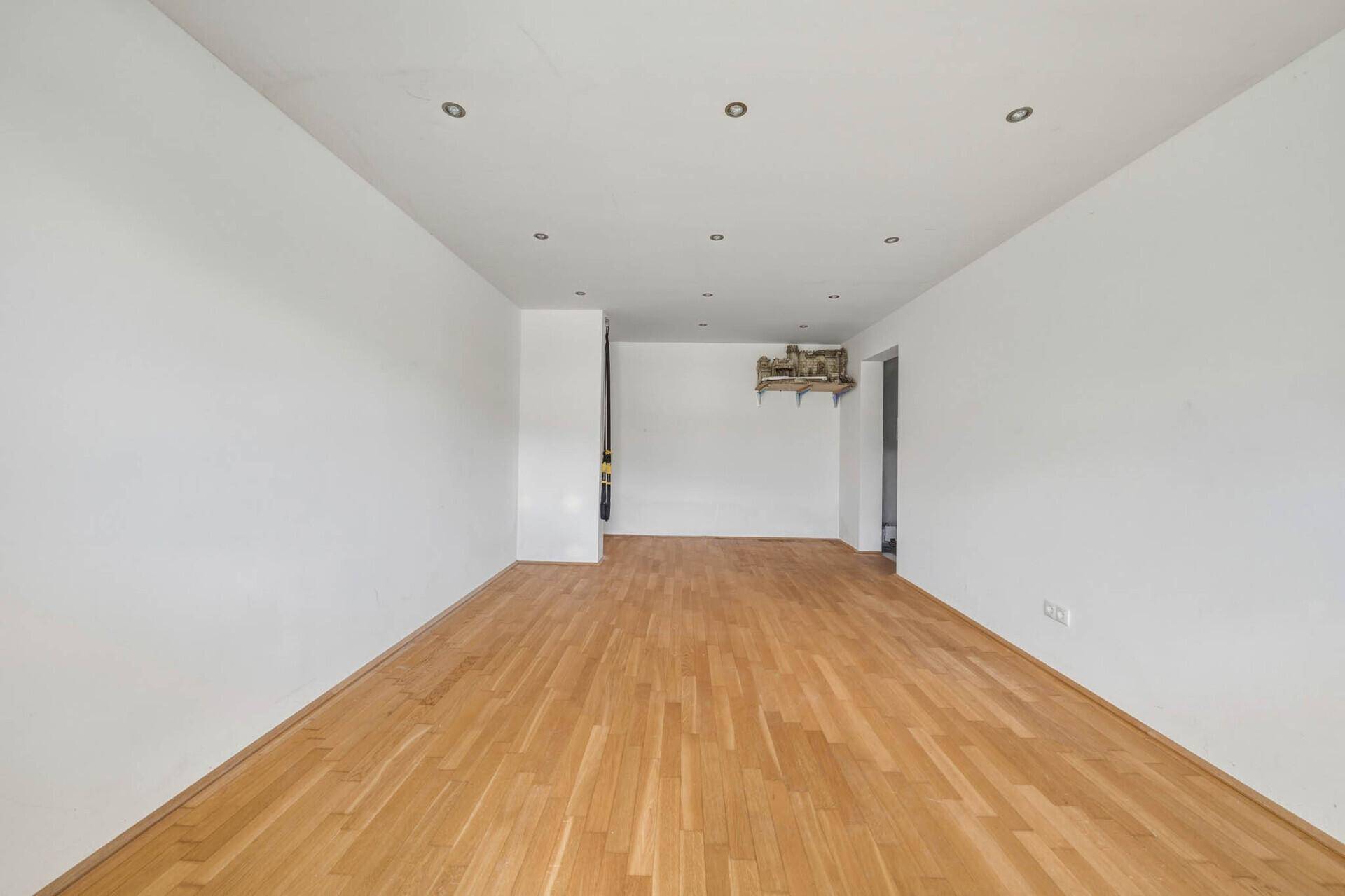 Geräumiges Zimmer mit warmem Holzboden und weiß gestrichenen Wänden, bereit zur individuellen Einrichtung.