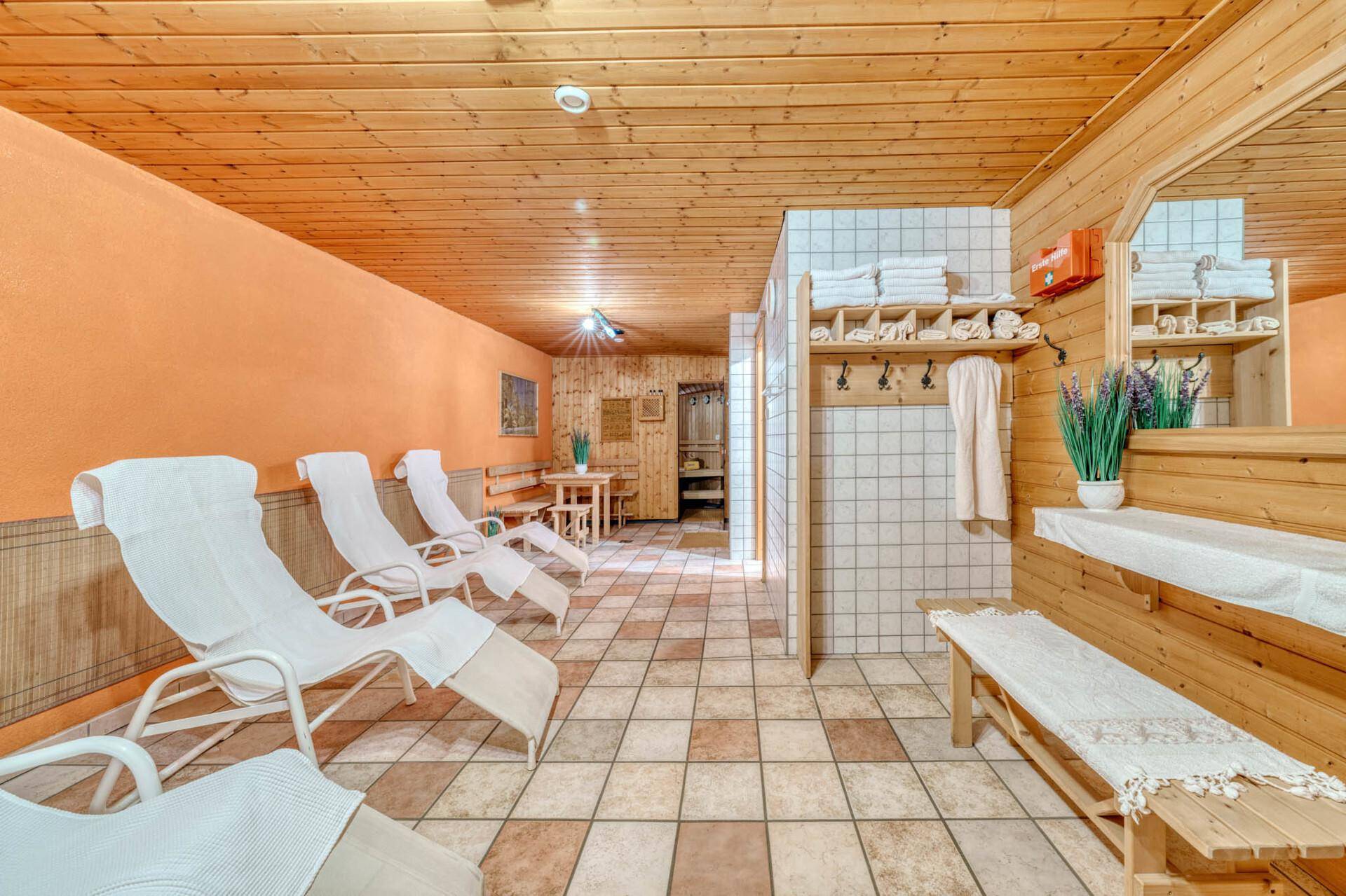 Geräumiger Wellnessbereich mit bequemen Liegestühlen, Holzvertäfelung und gefliestem Boden für Entspannung.