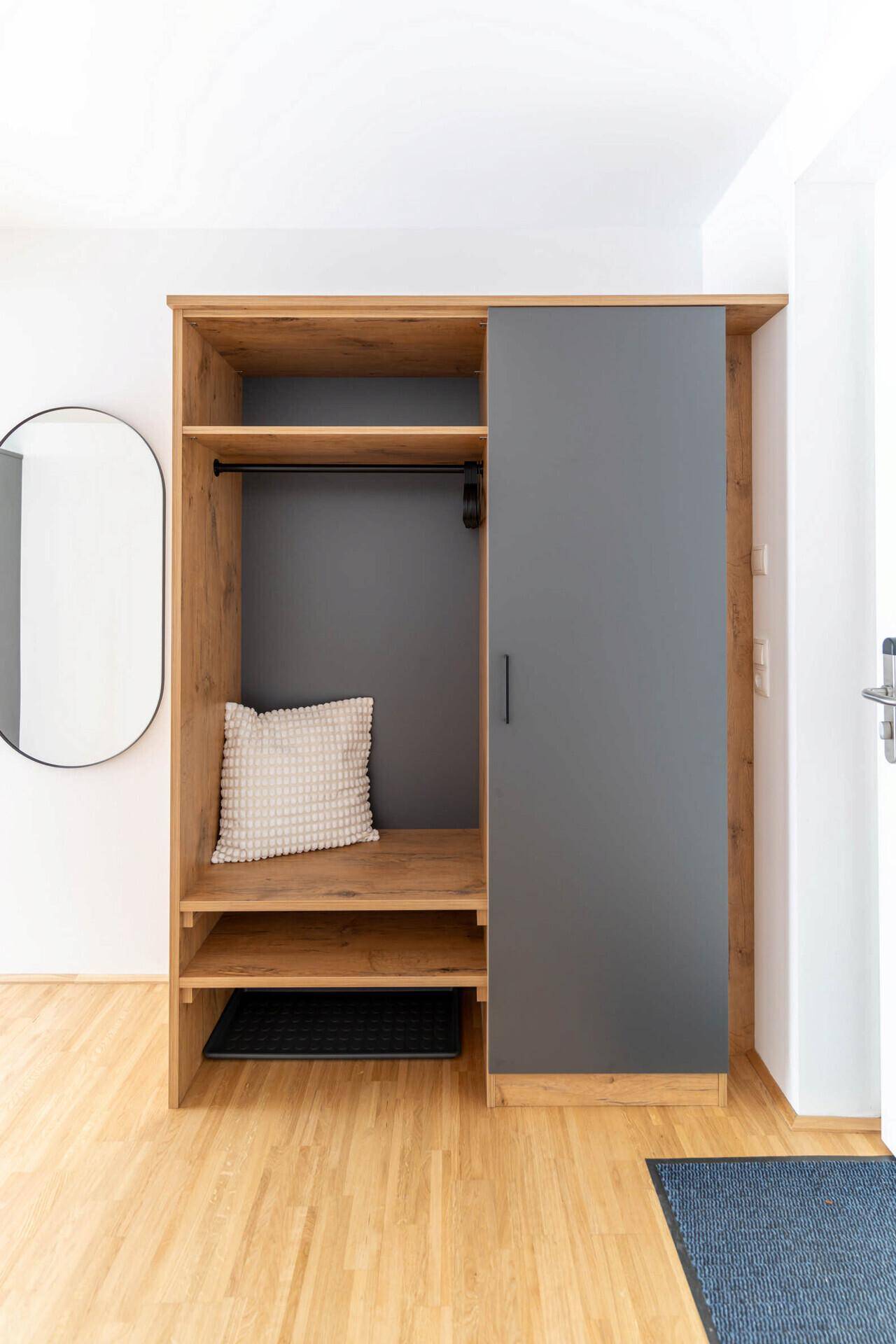 Eingangsbereich mit Holzboden, Garderobenschrank und ovalem Wandspiegel.