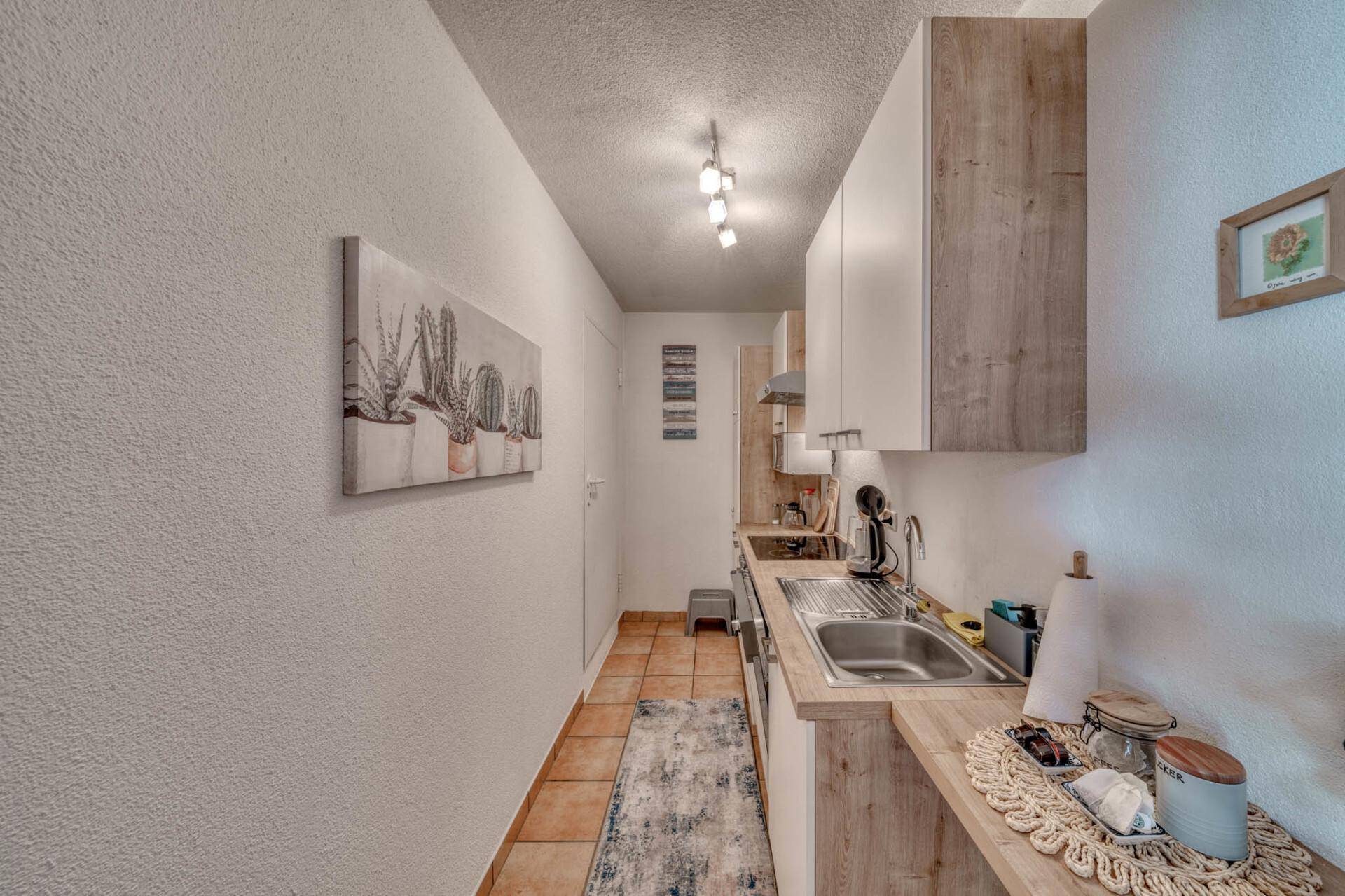 Schmale Küche mit modernen Holzfronten und Fliesenboden.