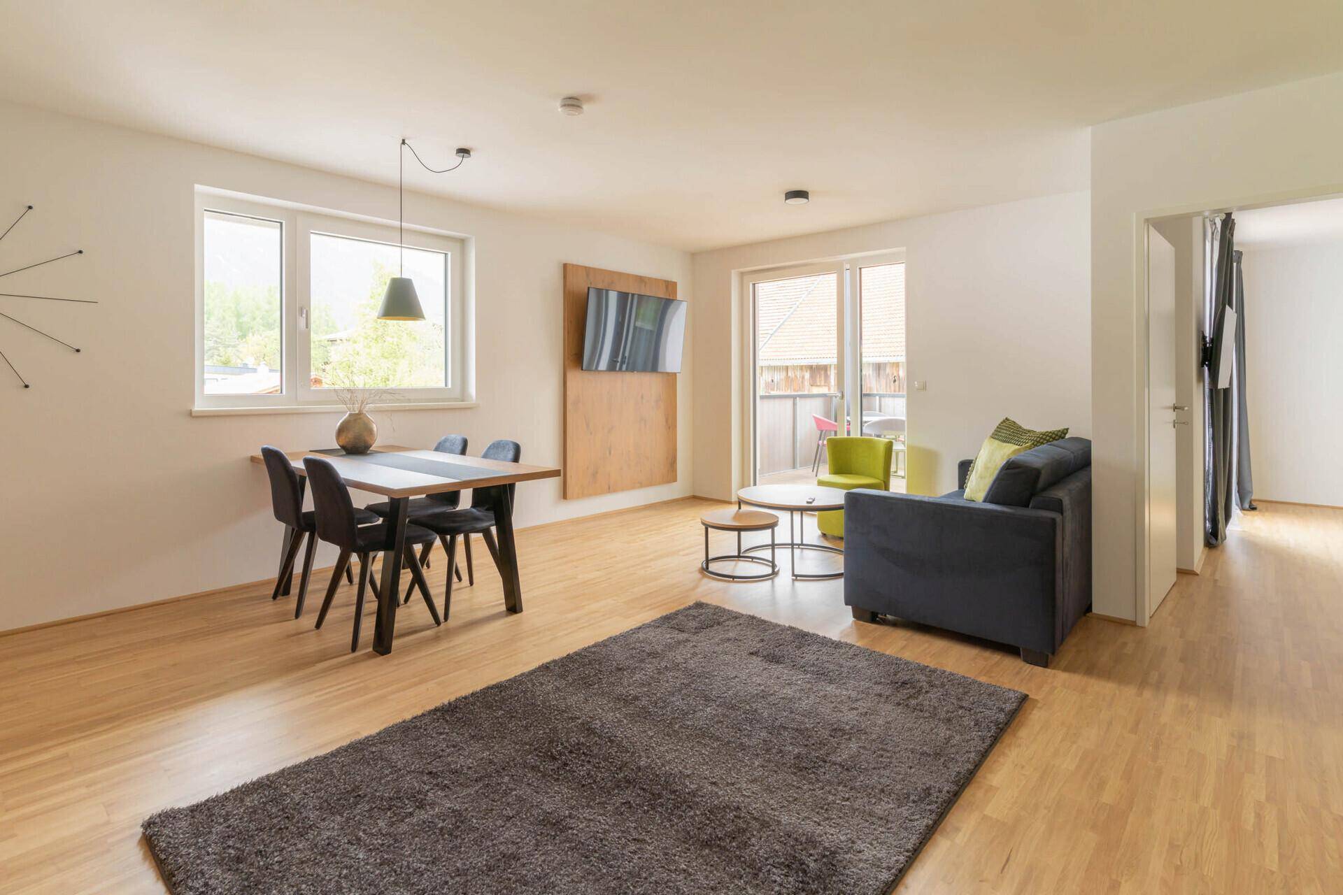 Moderne Küche mit Holzfronten, dunkler Arbeitsplatte und Esstisch im offenen Bereich.