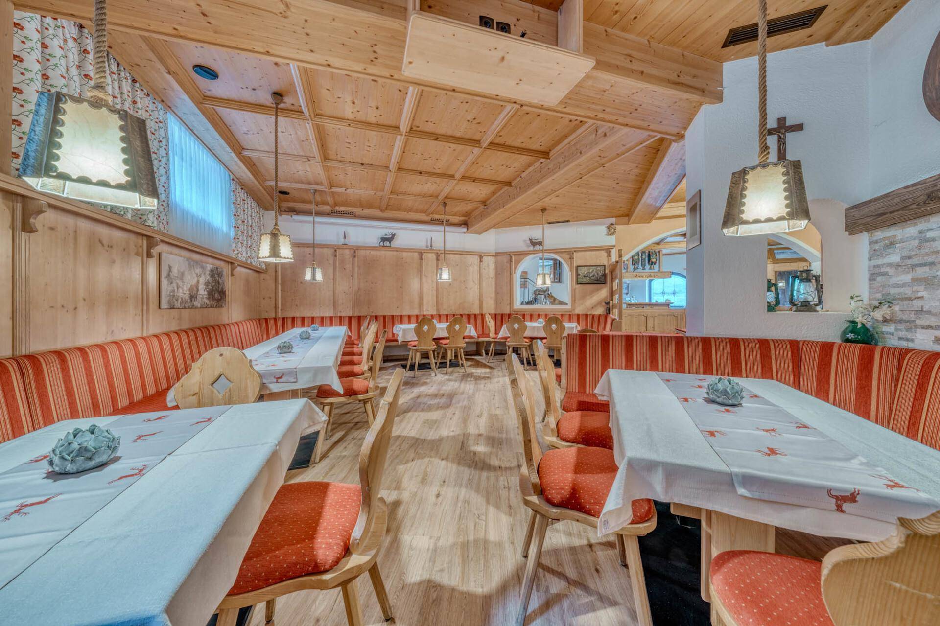 Gemütlicher Speisesaal mit Holzbalkendecke, langen Bänken und traditioneller Dekoration.