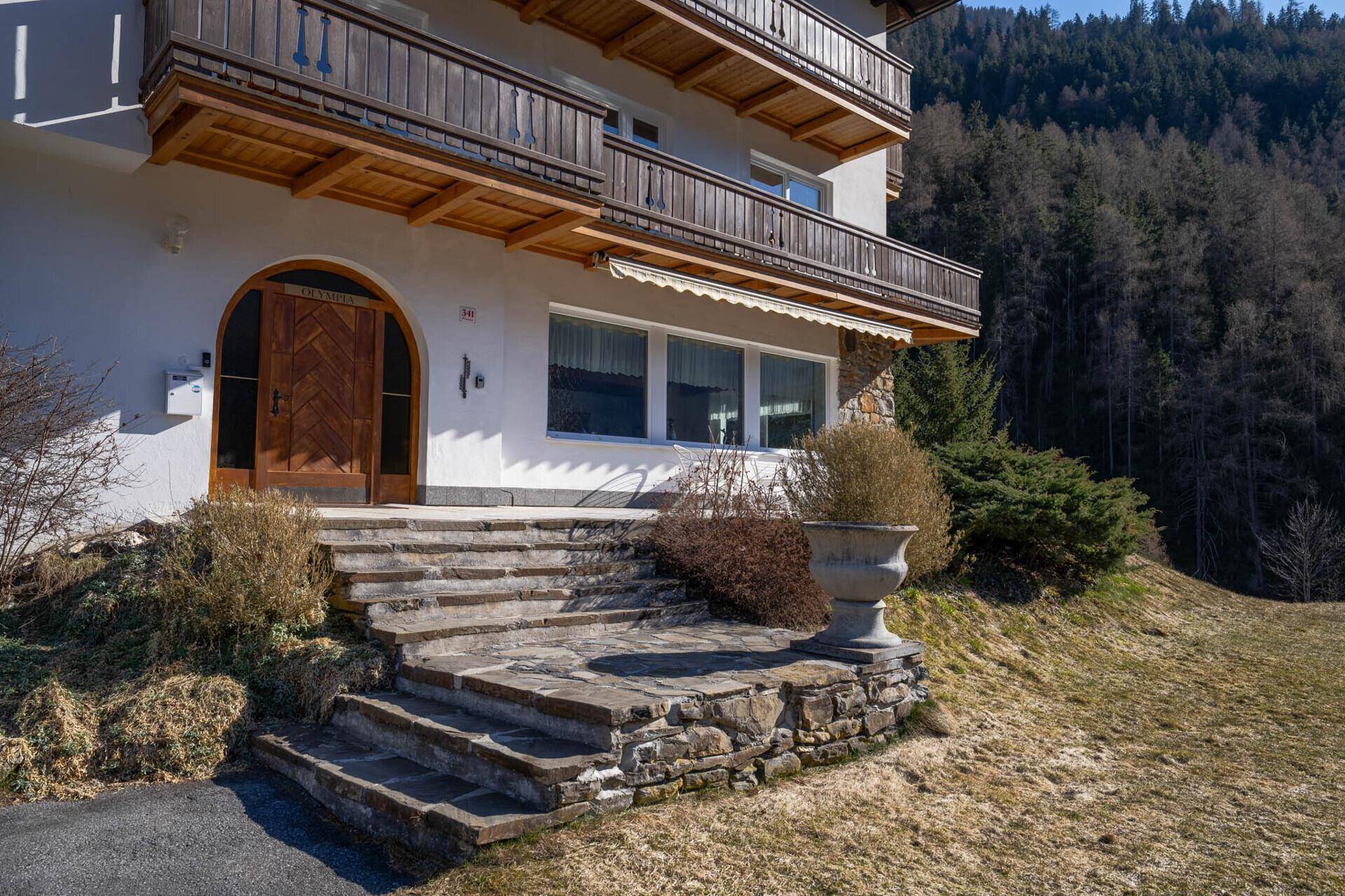Eingangsbereich des Hauses mit Steintreppe und traditioneller Holztür.