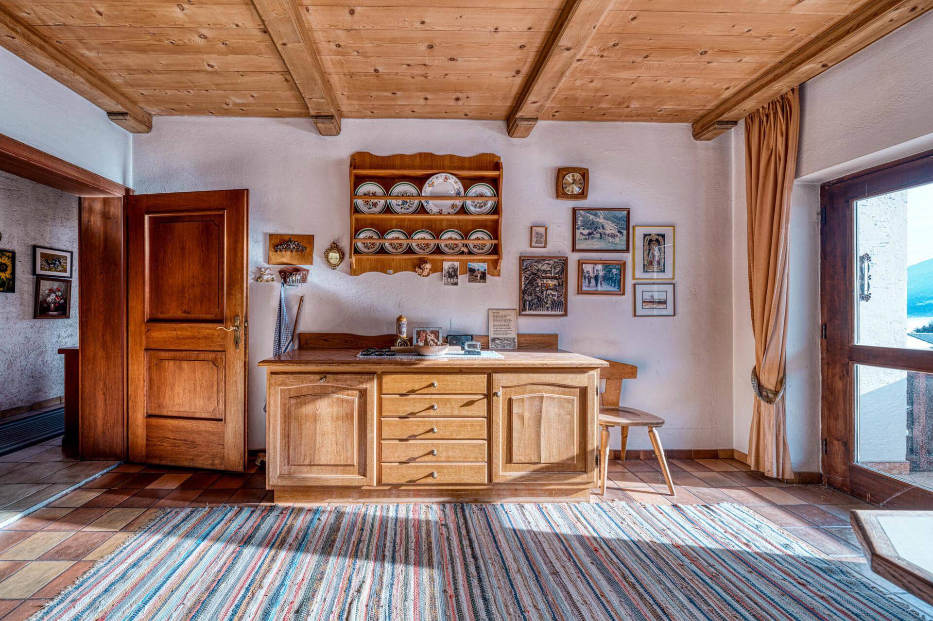 Traditioneller Wohnbereich mit Holzmöbeln, Fliesenboden und Zugang zu einem Balkon.