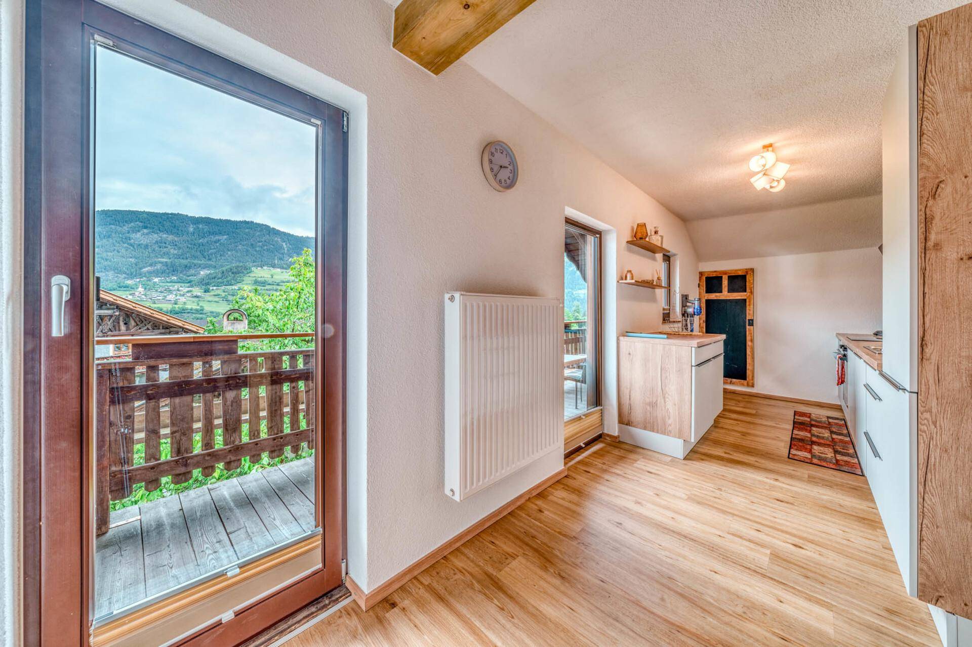 Helle Küche mit Holzboden, modernen Einbauschränken und Zugang zu einem Balkon.