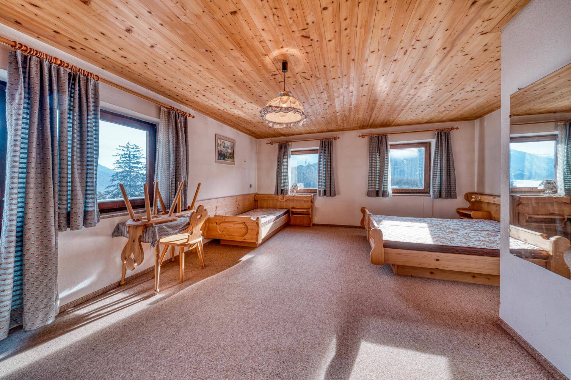 Helles Schlafzimmer im alpinen Stil mit Holzdecke, Teppichboden und Bergblick.