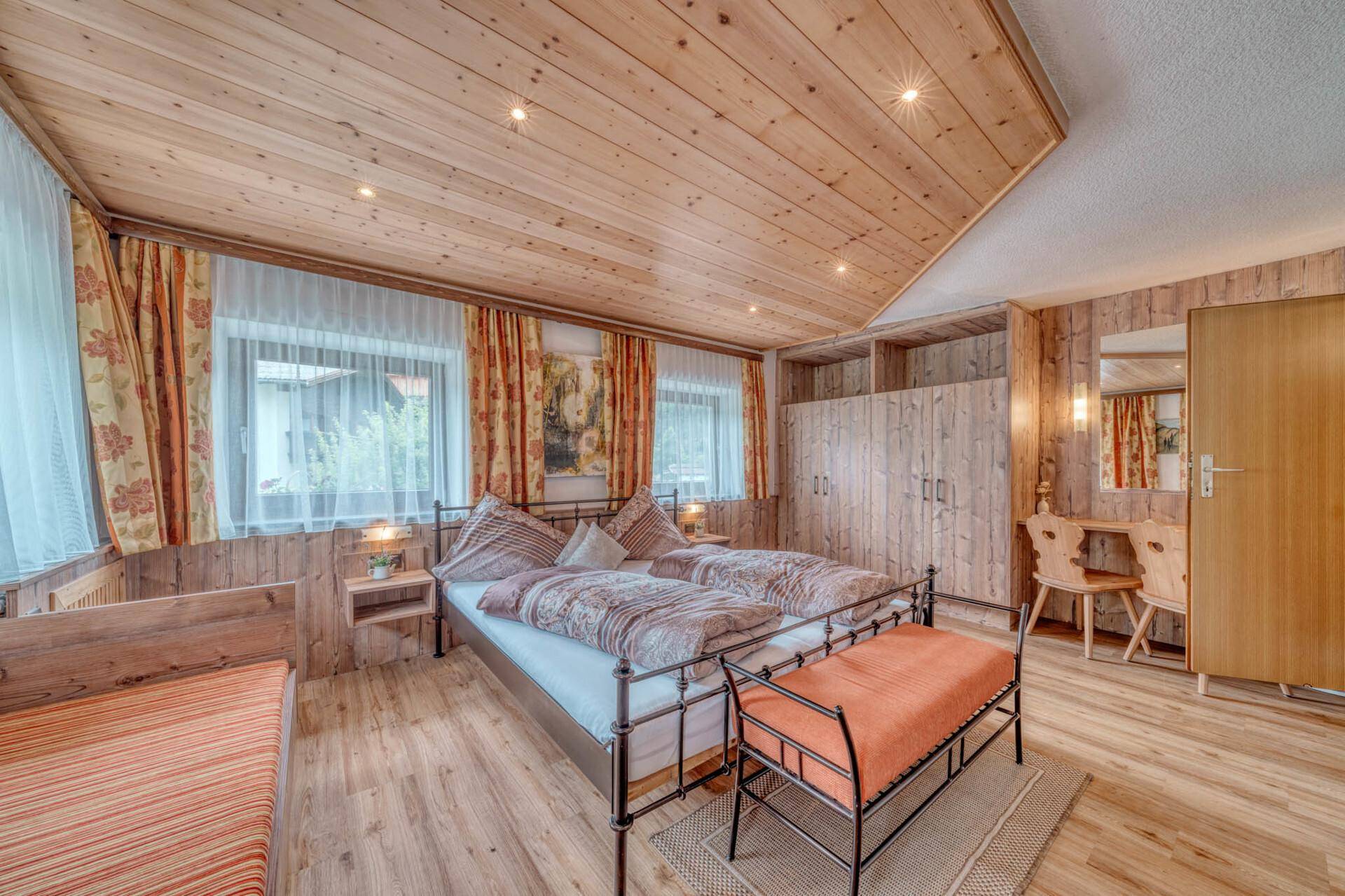 Schlafzimmer mit Doppelbett, Holzvertäfelung, Einbauschränken und Schreibtisch, traditionell eingerichtet.