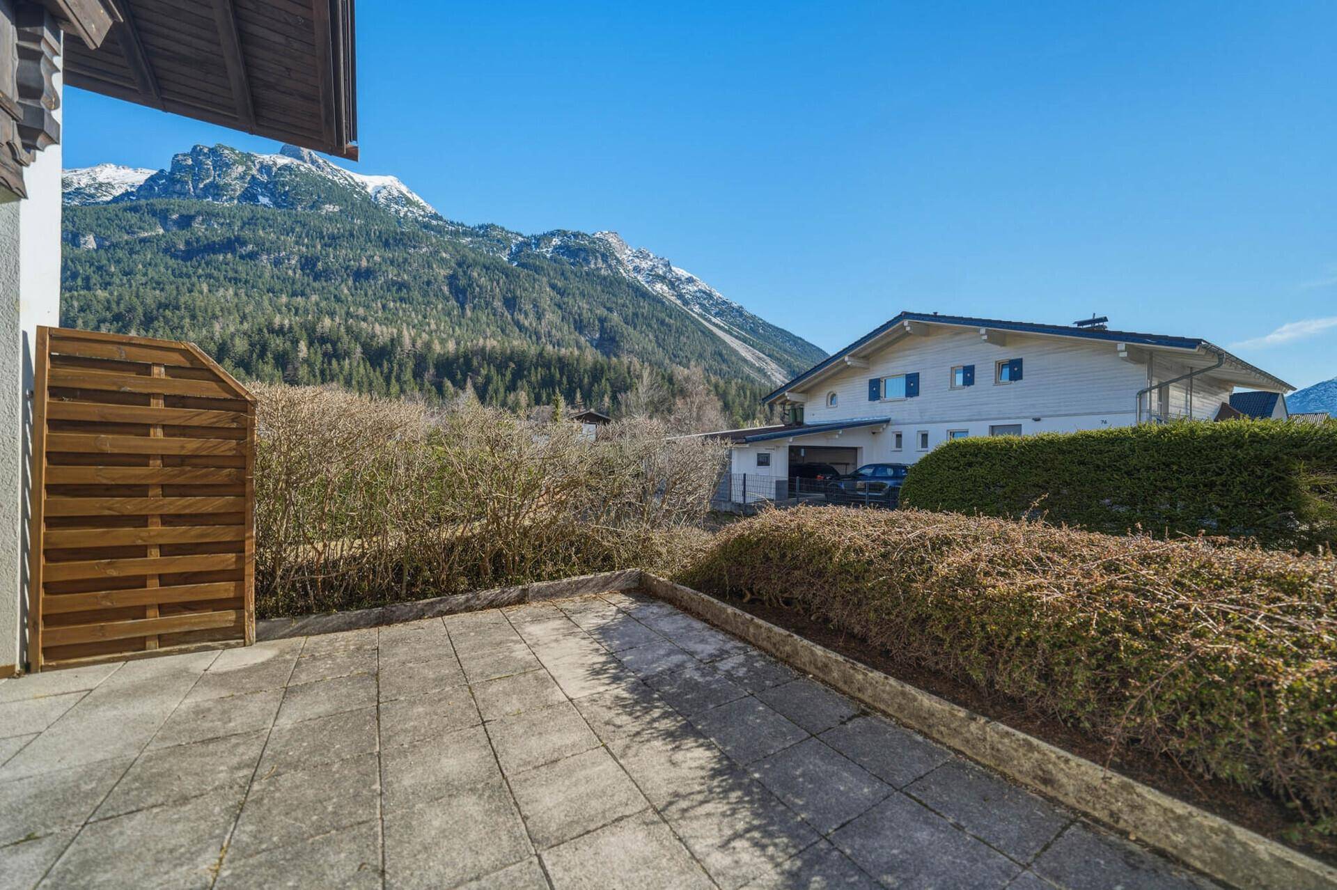 Sonniger Außenbereich mit gepflasterter Terrasse und weitem Bergblick.