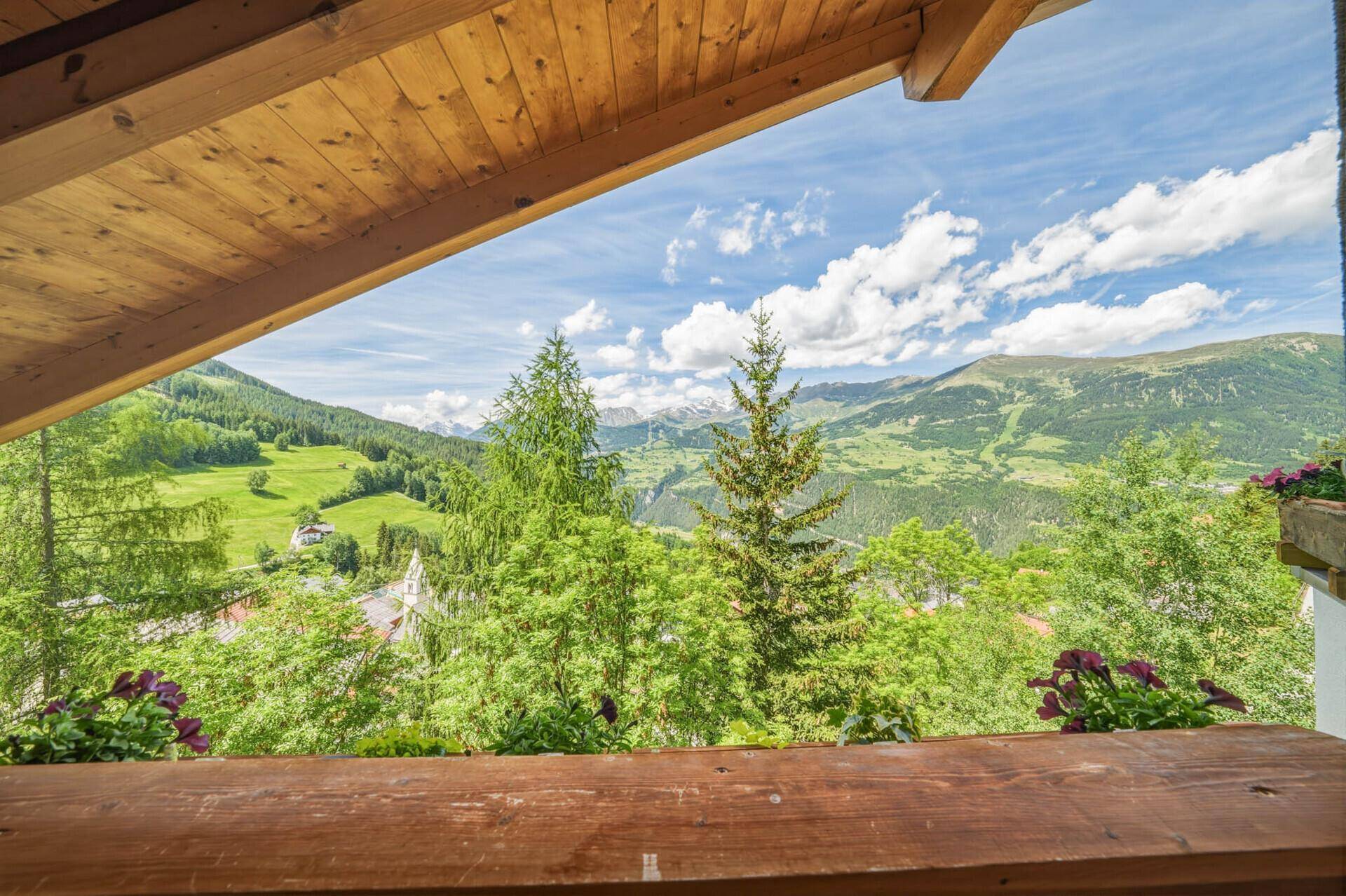 Panoramablick vom Balkon auf die grüne Berglandschaft und die umliegenden Gipfel.