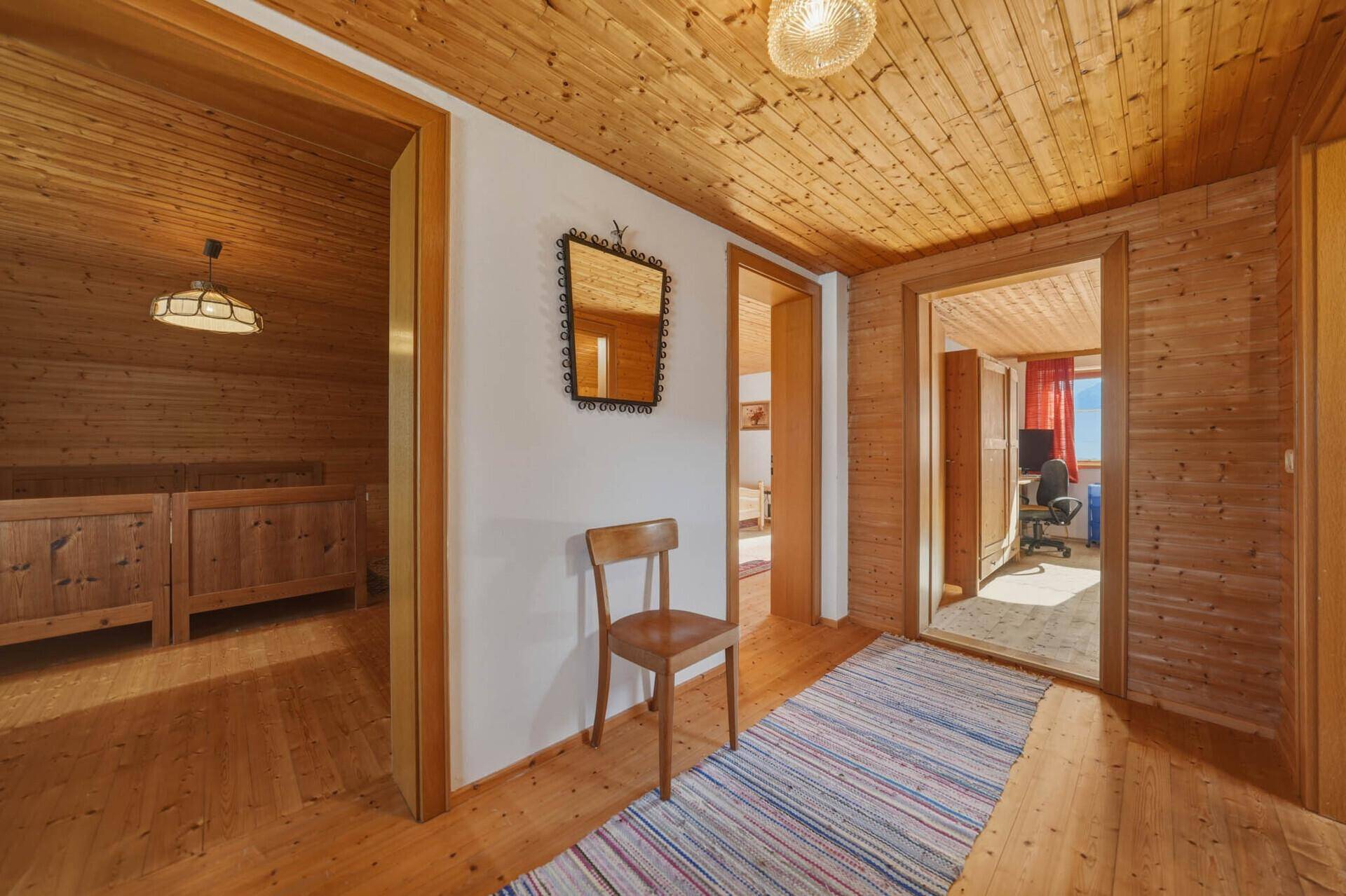 Heller Flur mit Holztäfelung, Holzfußboden und Zugang zu mehreren Räumen.
