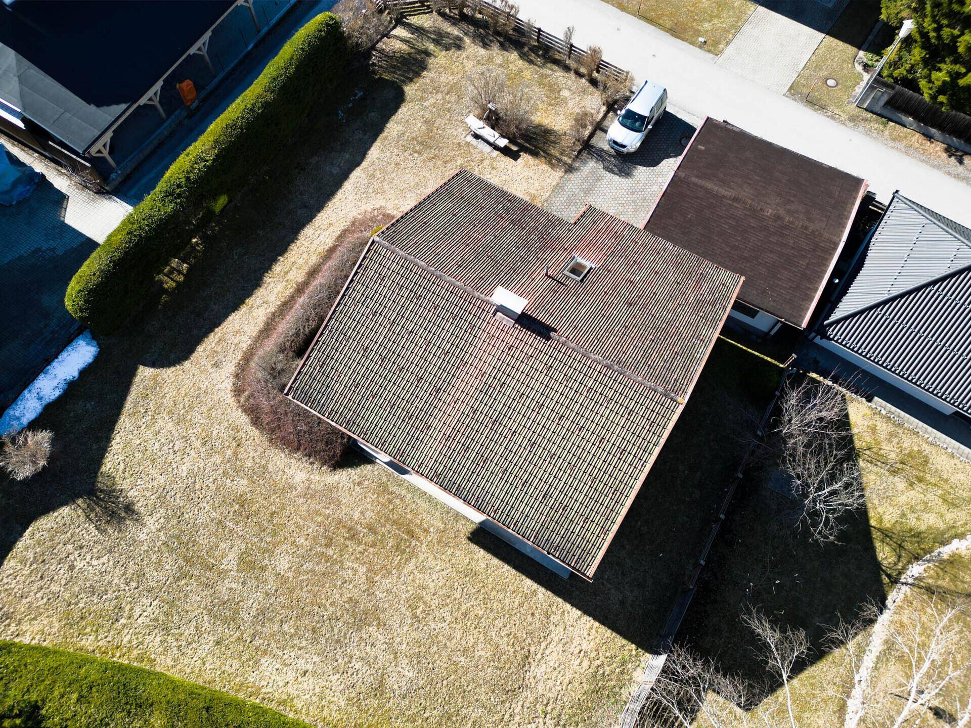 Draufsicht des Hauses mit Dach, Garten und umliegender Landschaft.