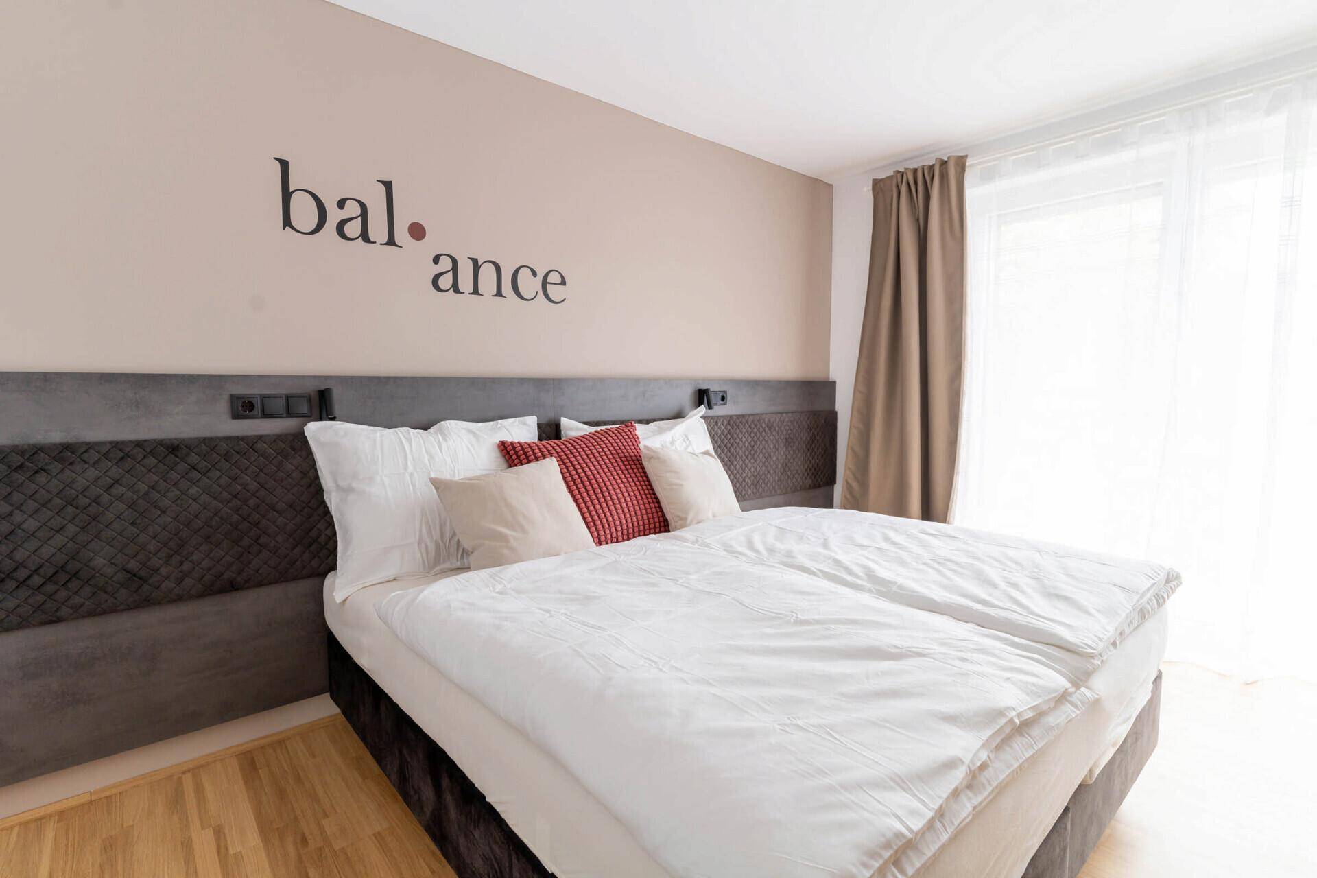 Gemütliches Schlafzimmer mit Doppelbett, Holzboden und dekorativer Wandgestaltung.