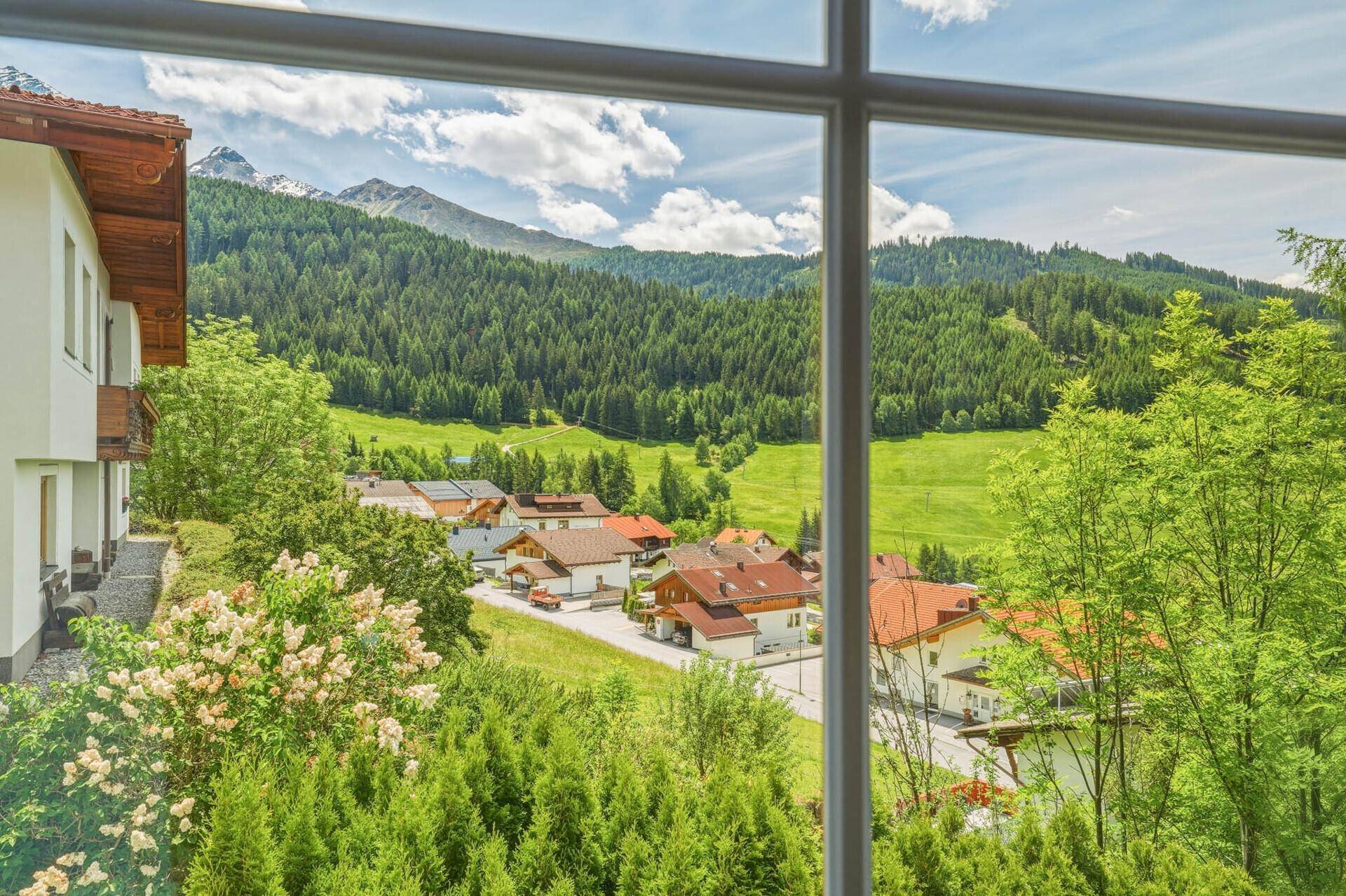 Weitläufiger Ausblick aus dem Fenster auf ein idyllisches Dorf und die umliegende Natur.
