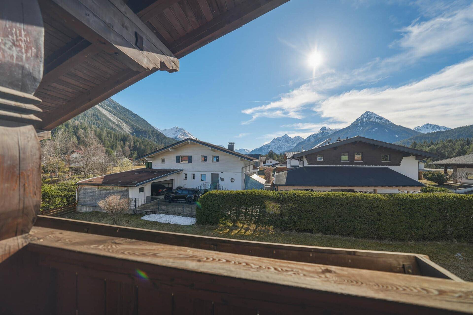 Sonniger Balkon mit Holzbalken und weitem Blick auf die umliegende Bergwelt.