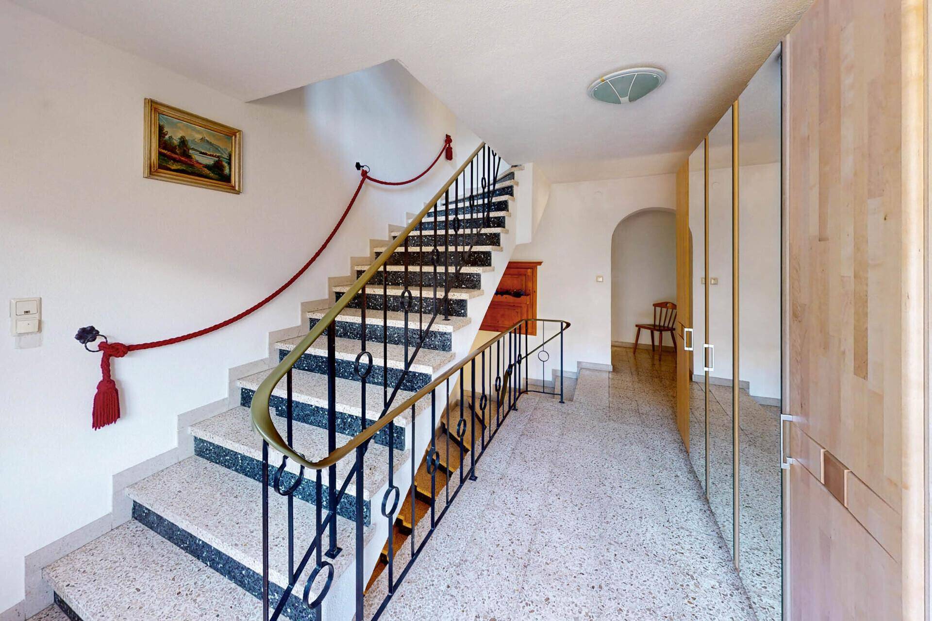 Geräumiger Flur mit Treppe, Terrazzoboden und Spiegelschränken.