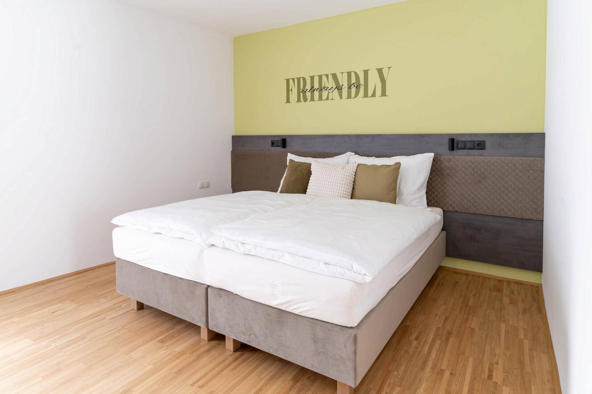 Gemütliches Schlafzimmer mit Doppelbett, Holzboden und einer freundlichen Wanddekoration.