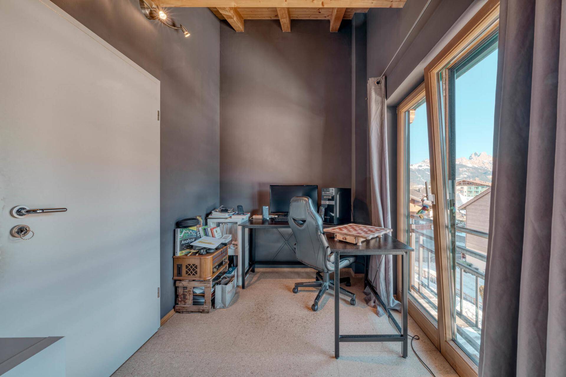 Helles Arbeitszimmer mit Schreibtisch, Bürostuhl und Blick auf die Berge.