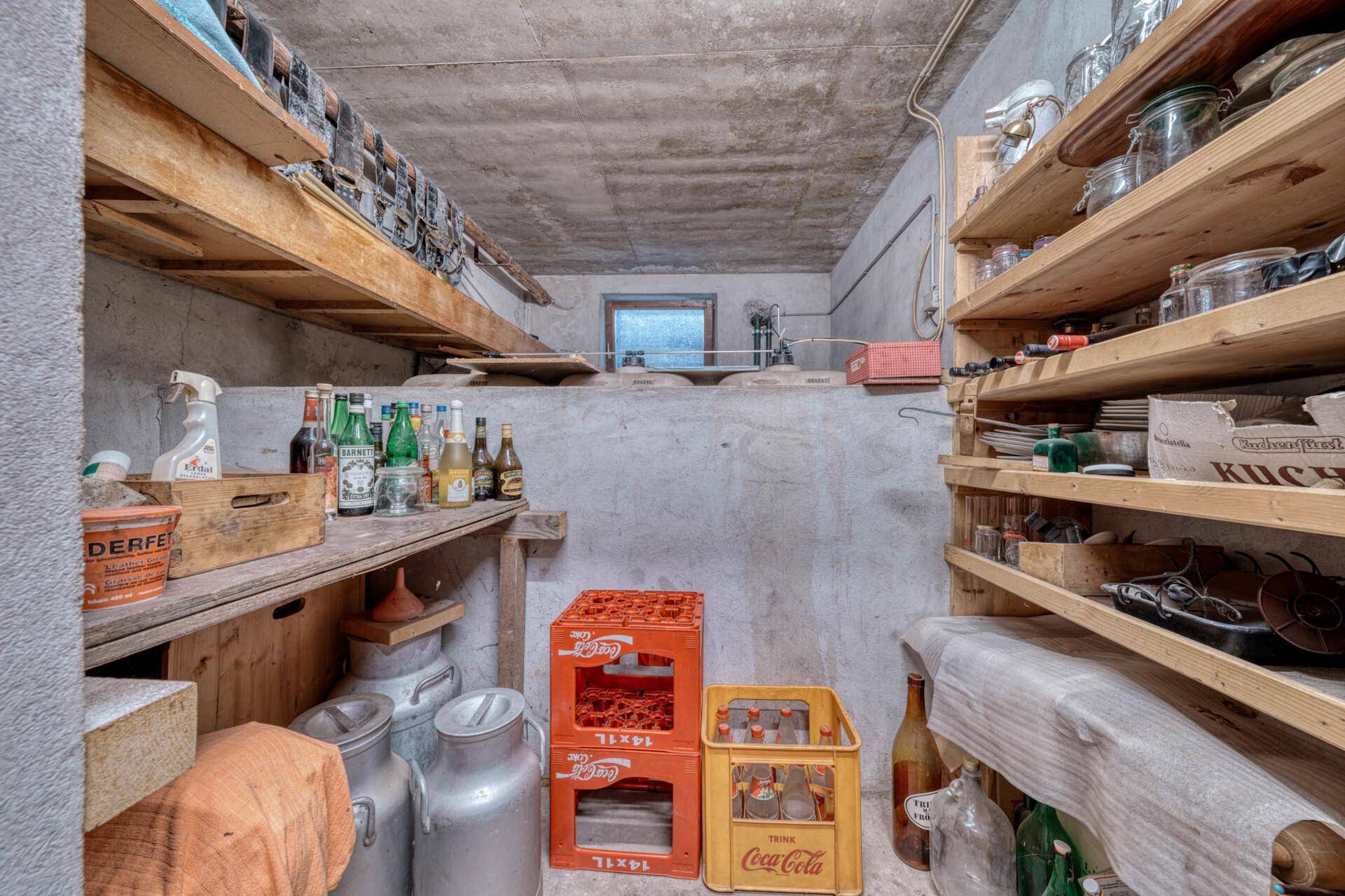 Lagerraum im Keller mit Holzregalen, Flaschen und Vorräten.