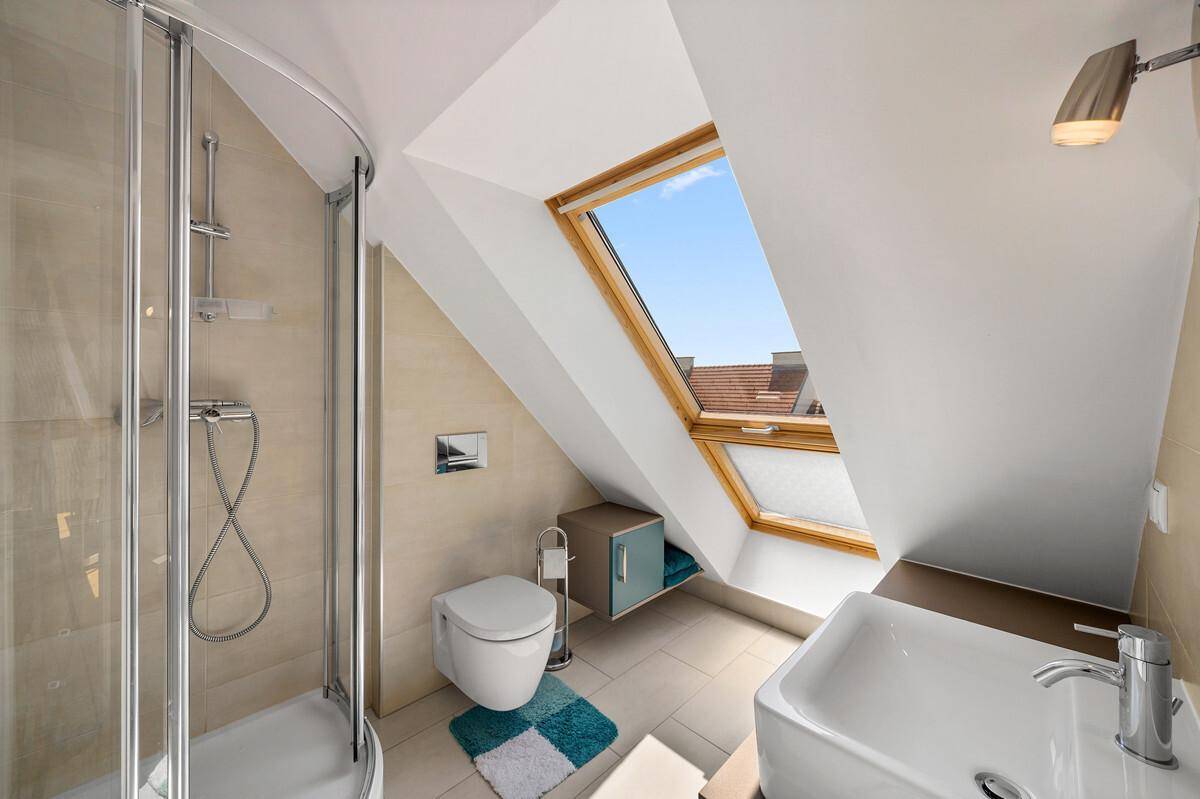 Helles Badezimmer im Dachgeschoss mit Dusche, WC und Dachfenster.