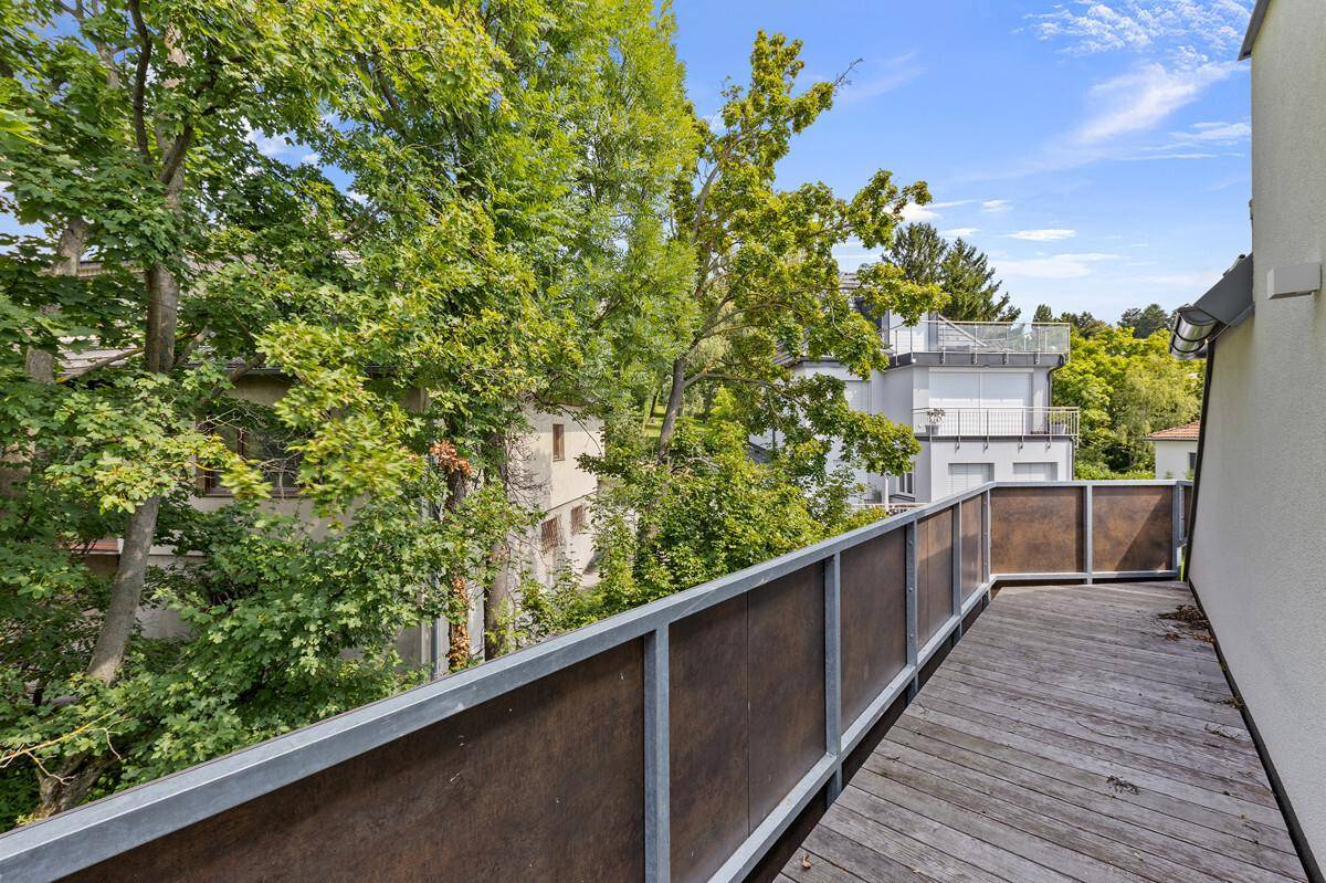 Schmaler Balkon mit Holzboden und direktem Blick in die Baumwipfel.