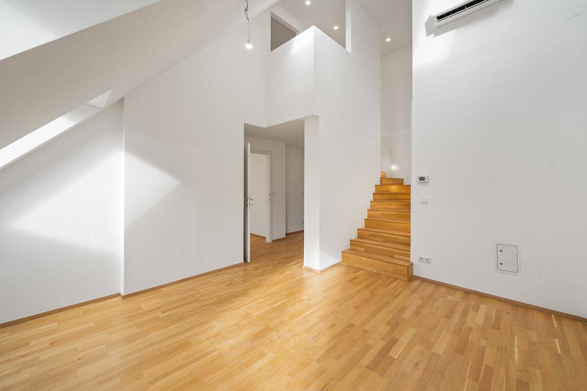 Heller Wohnbereich mit Holztreppe, hohen Decken und modernem Design.
