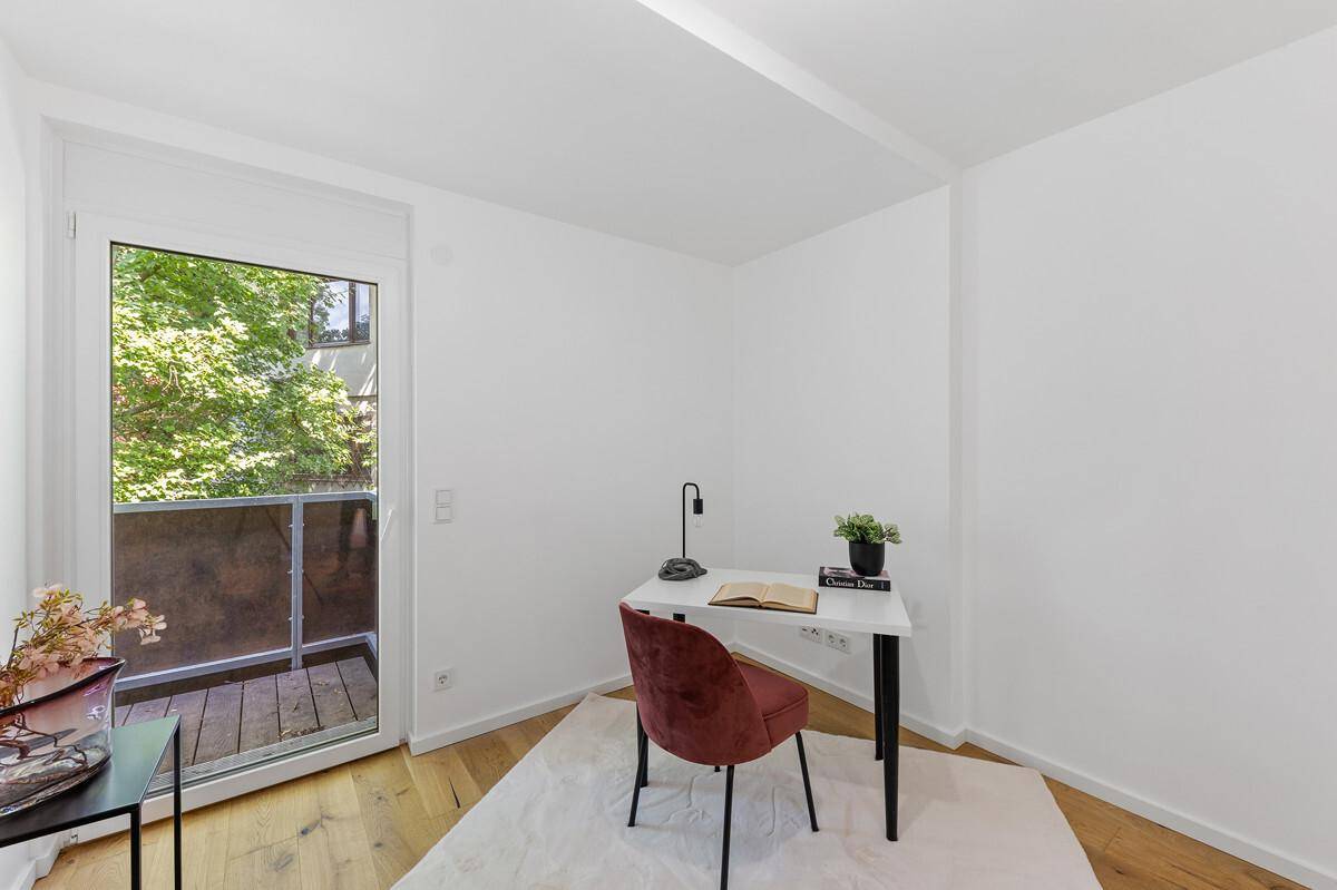 Funktionales Arbeitszimmer mit Schreibtisch, Holzboden und direktem Balkonzugang.