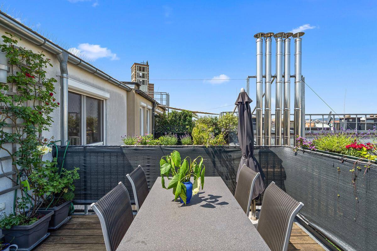 Gemütlicher Essbereich auf der Dachterrasse mit Sonnenschirm und Stadtblick.