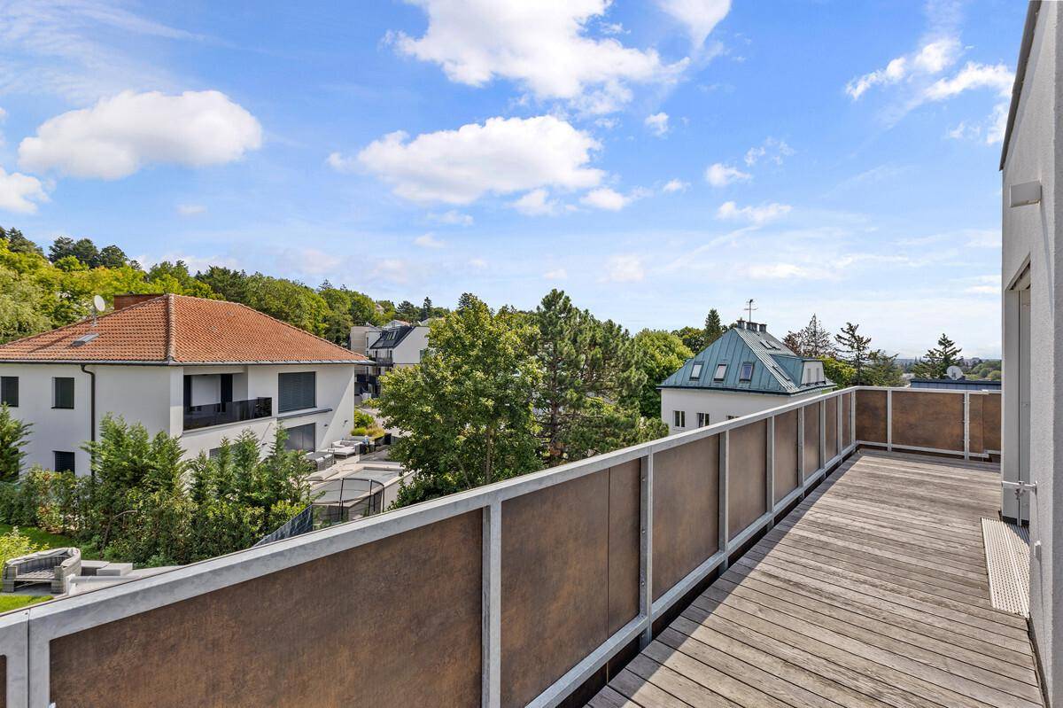 Balkon mit Holzboden und Ausblick auf die Nachbarschaft und grüne Hügel.