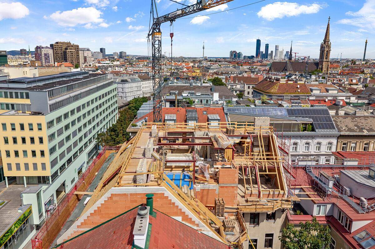 Baustelle auf dem Dach eines Gebäudes mit Blick auf die Skyline und umliegende Dächer.