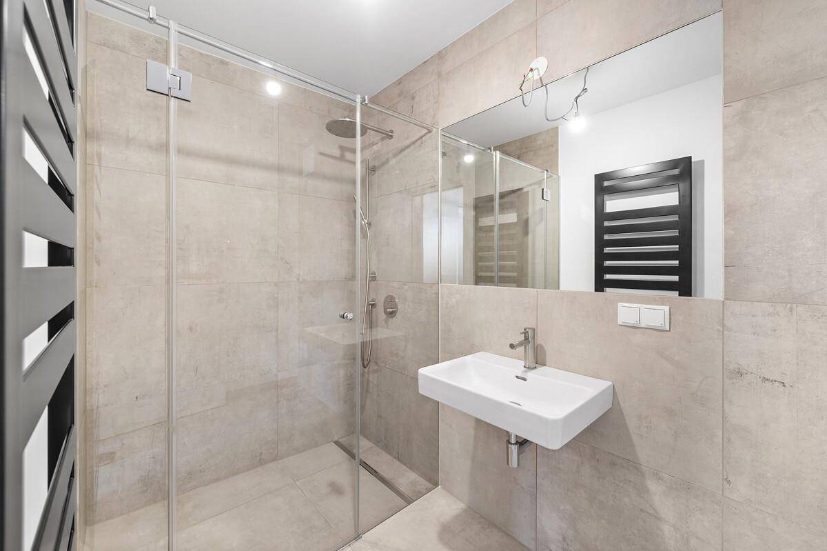 Modernes Badezimmer mit begehbarer Dusche, Wandwaschbecken und beheiztem Handtuchhalter.