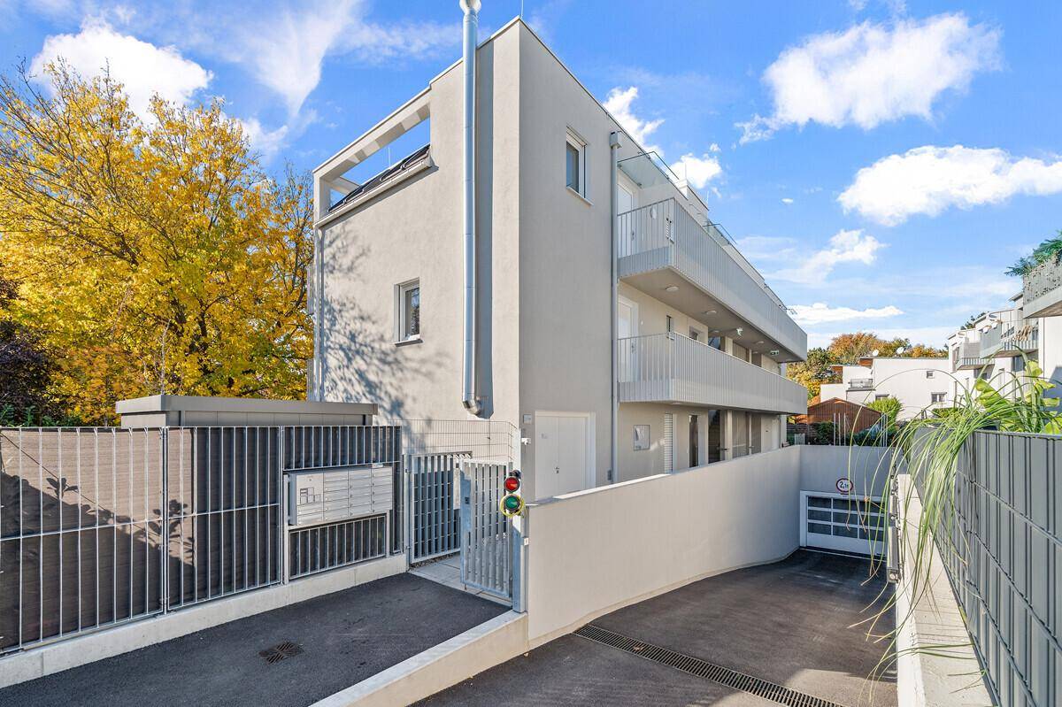 Moderne Wohnanlage mit heller Fassade, Tiefgaragenzufahrt und gepflegtem Eingangsbereich.