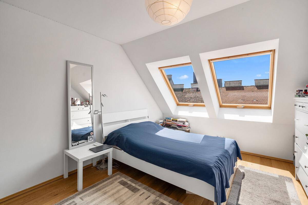 Schlafzimmer im Dachgeschoss mit Doppelbett, Kommode und Holzboden.