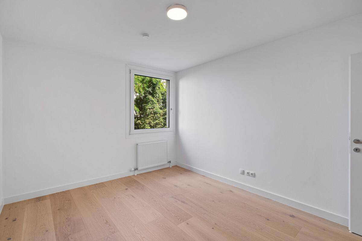 Ruhiges Zimmer mit Parkettboden und Fenster mit Blick ins Grüne.