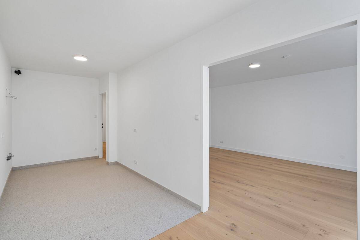 Übergangsbereich mit Fliesenboden, der zu einem Zimmer mit Parkett führt.