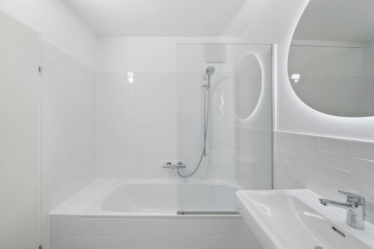 Helles Badezimmer mit Badewanne, Duschfunktion und modernem Waschtisch.