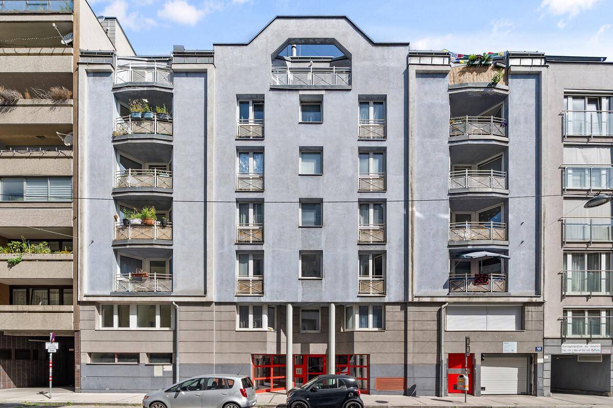 Moderne Wohnfassade mit Balkonen und großen Fenstern in städtischer Umgebung.