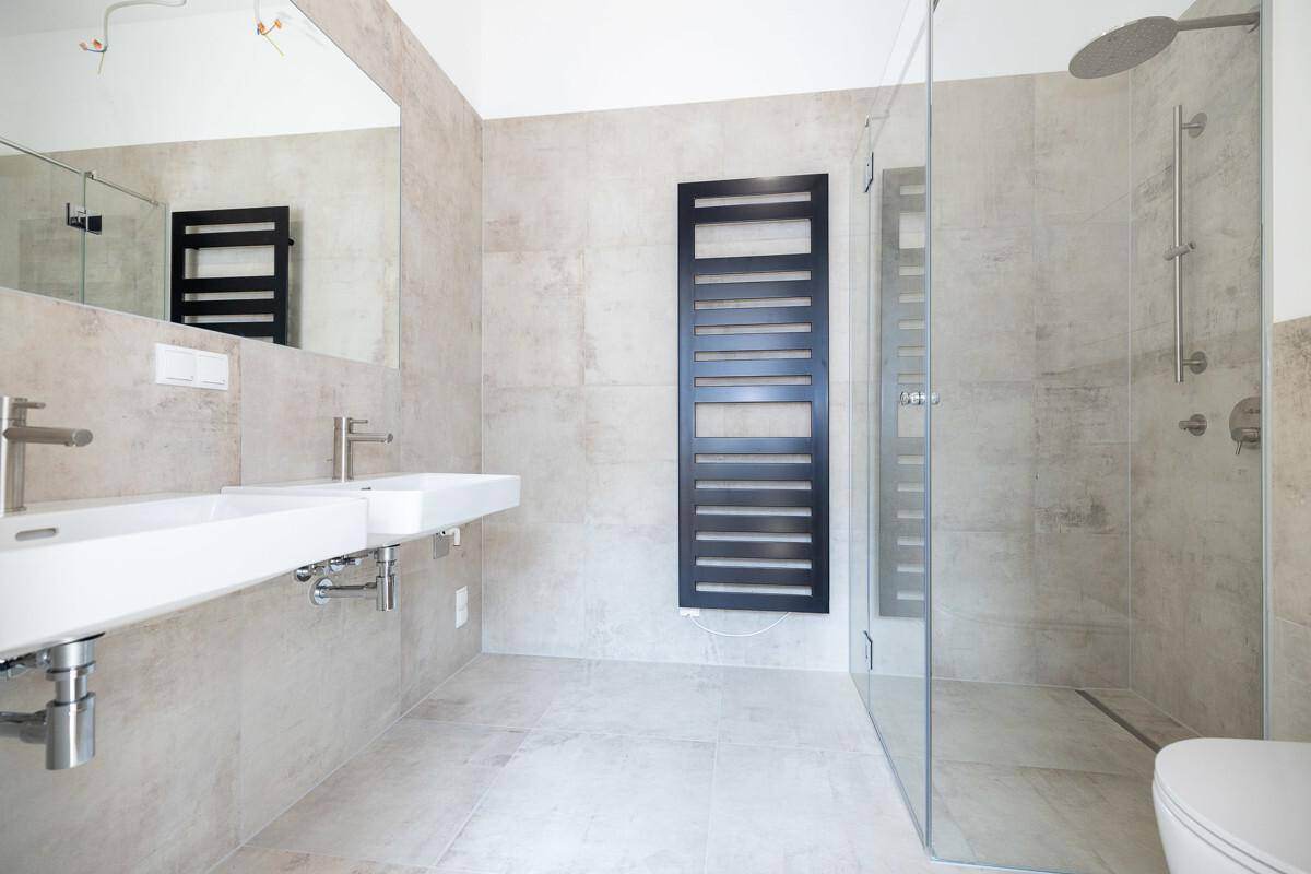 Modernes Badezimmer mit Doppelwaschbecken, großer begehbarer Dusche und beheiztem Handtuchhalter.