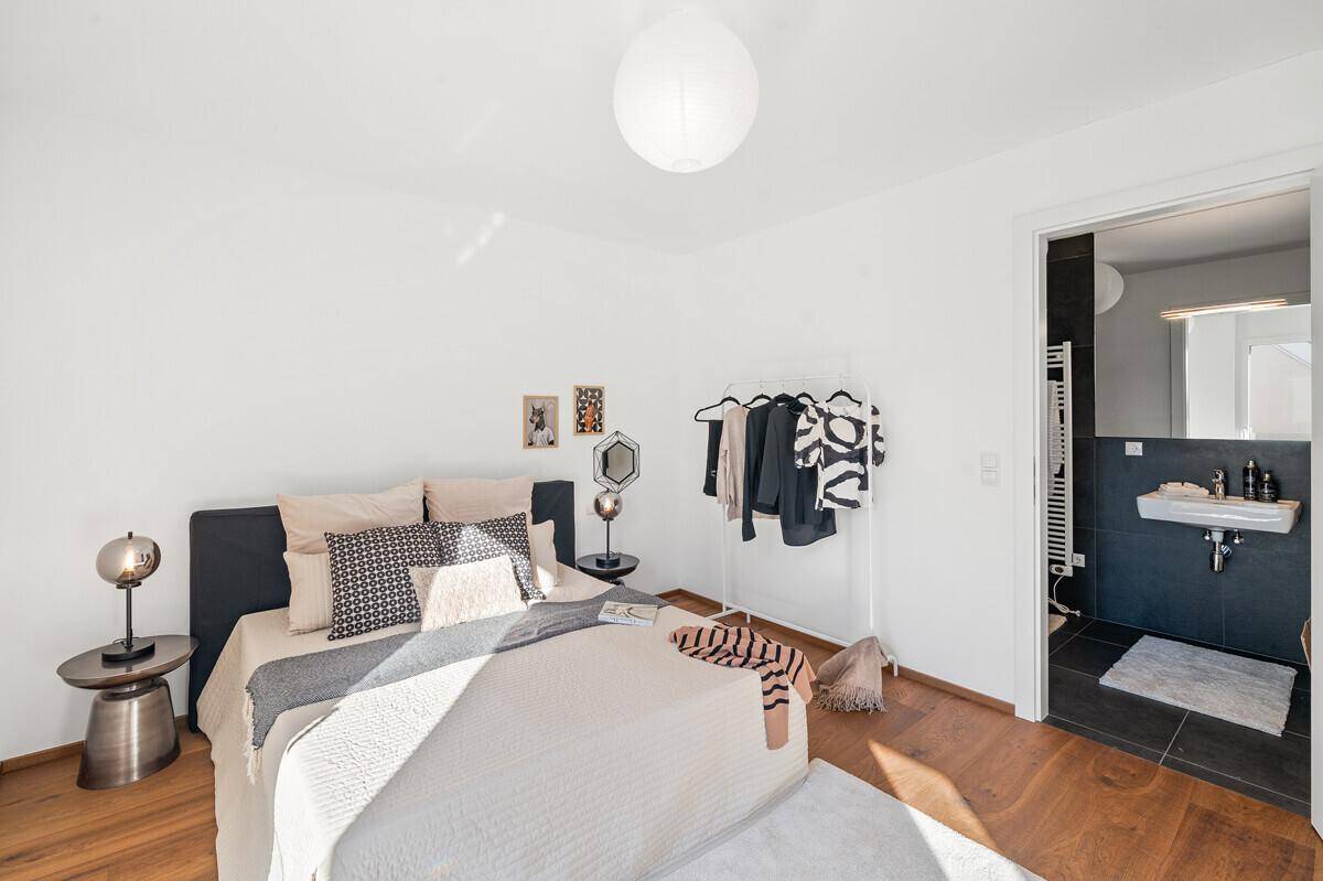 Gemütliches Schlafzimmer mit Holzboden und direktem Zugang zu einem modernen Badezimmer.