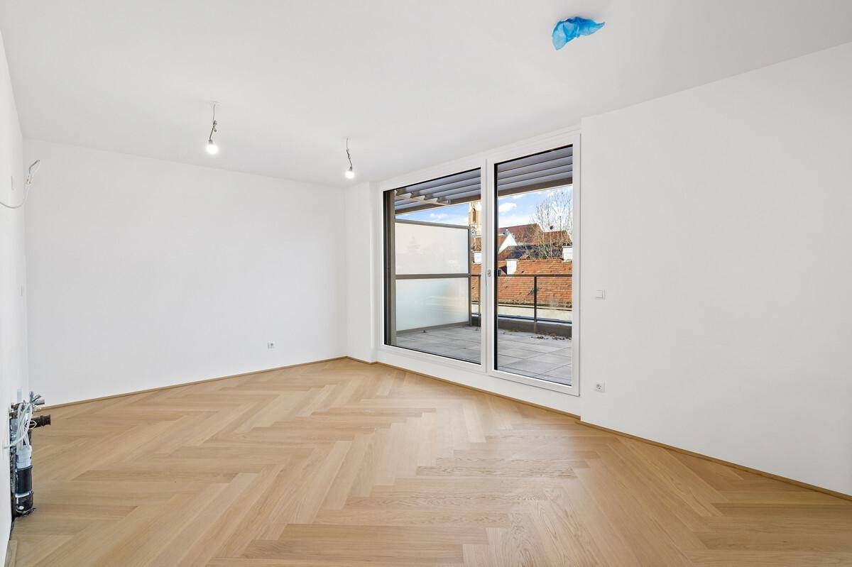 Lichtdurchfluteter Raum mit elegantem Fischgrätparkett und Zugang zur sonnigen Terrasse.