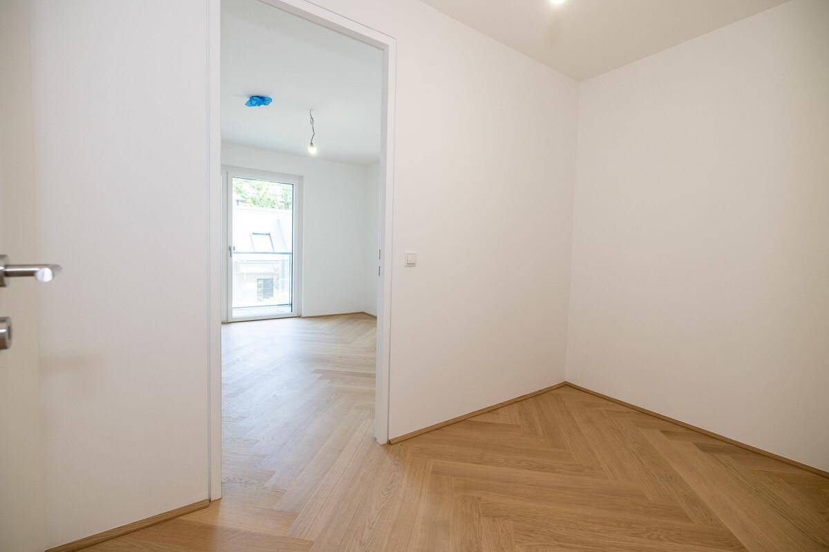 Leerer Innenraum mit Fischgrätparkett und weiß gestrichenen Wänden, bietet viel Gestaltungspotenzial.